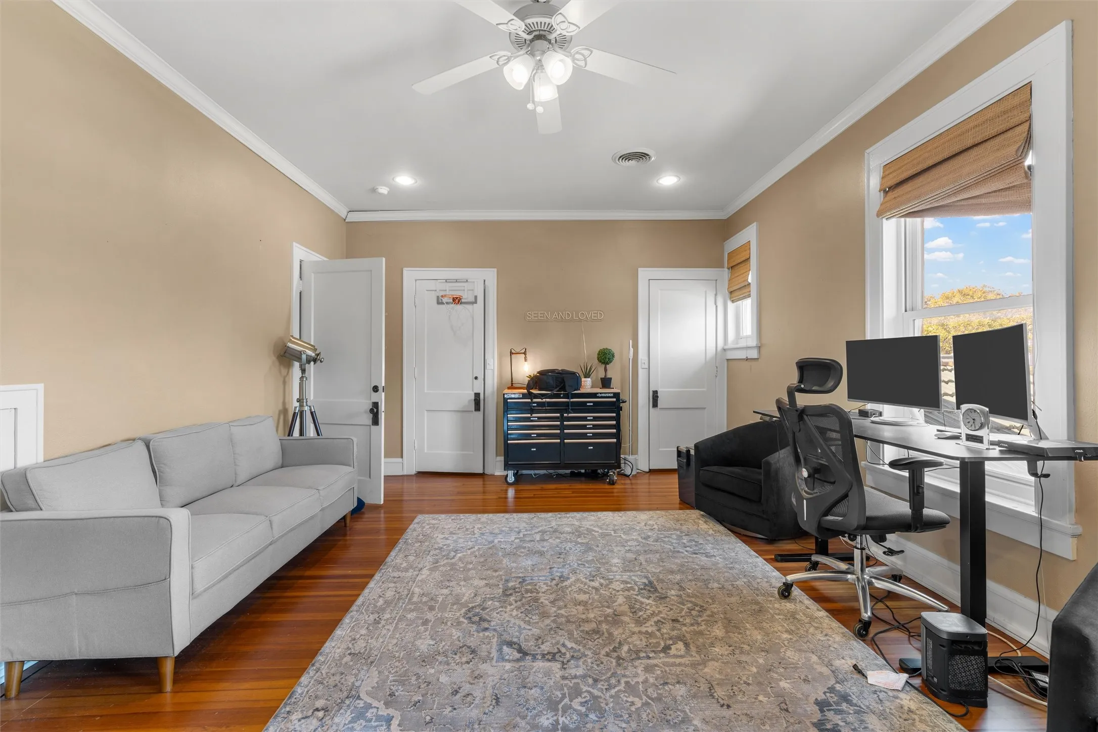 Hardwood flooring, painted walls, ceiling fan with integrated lighting, and two windows providing natural light
