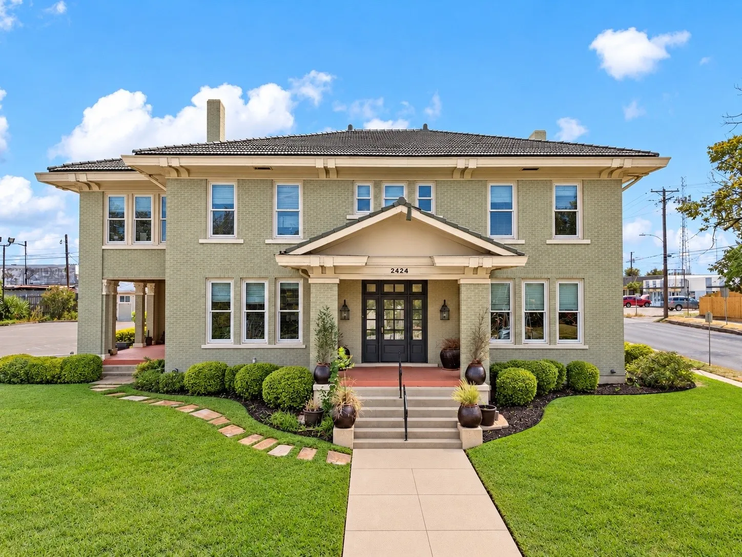 Brick exterior with a prominent front entrance, featuring a covered porch, multiple windows, and a landscaped front yard with a walkway