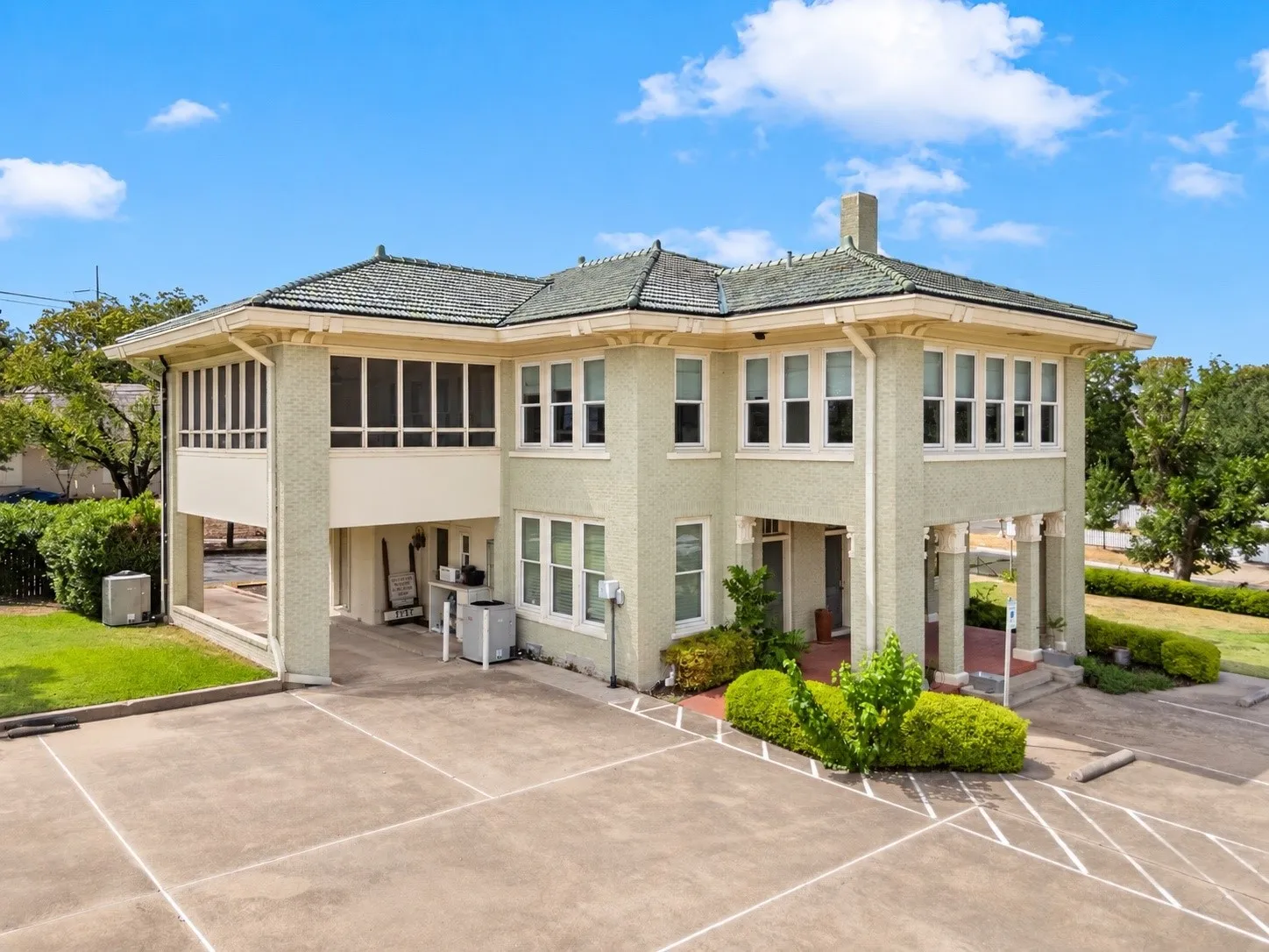 Two-story building with a covered entry, screened porch, and ample paved parking