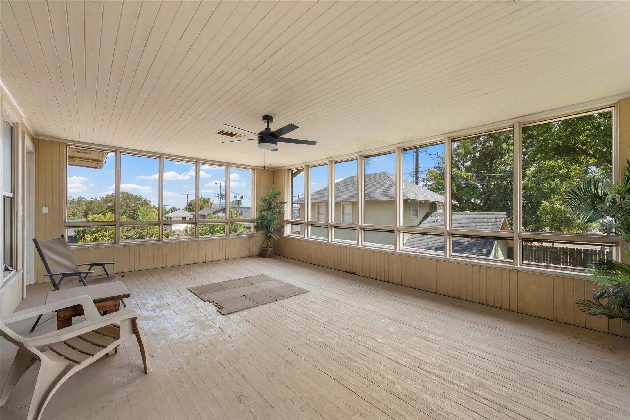 Enclosed porch with extensive window panels, wood-finish flooring, beadboard ceiling, and a ceiling fan