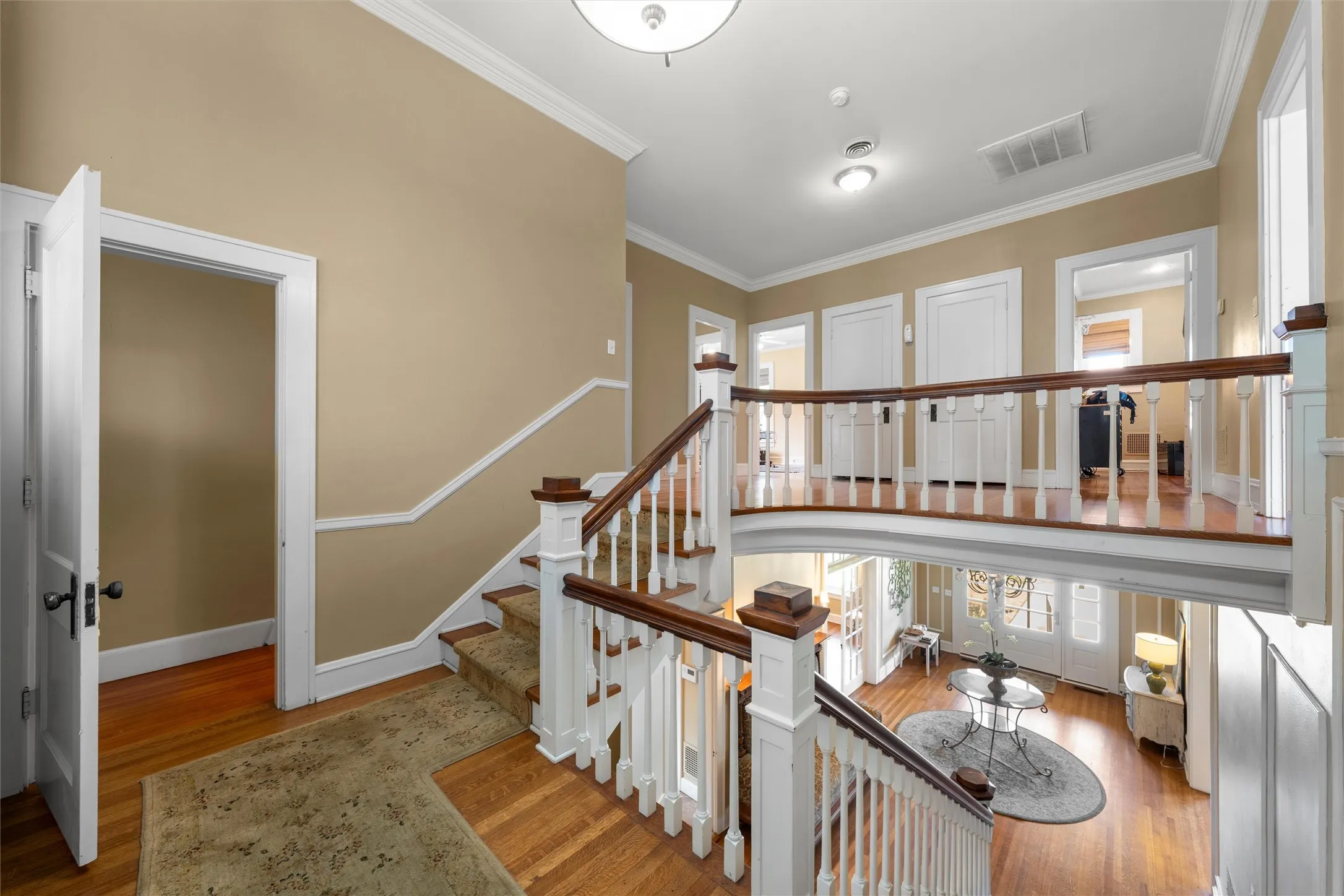 Grand two-story foyer with hardwood flooring, a curved second-story landing, white balusters, and wood handrails