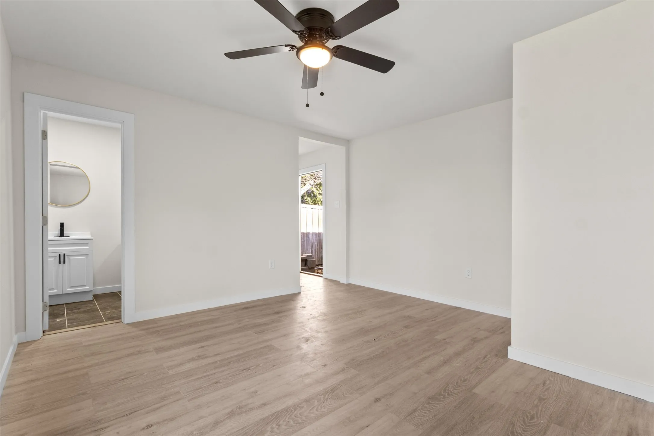 Wood-finish flooring, white walls, and a ceiling fan with integrated lighting