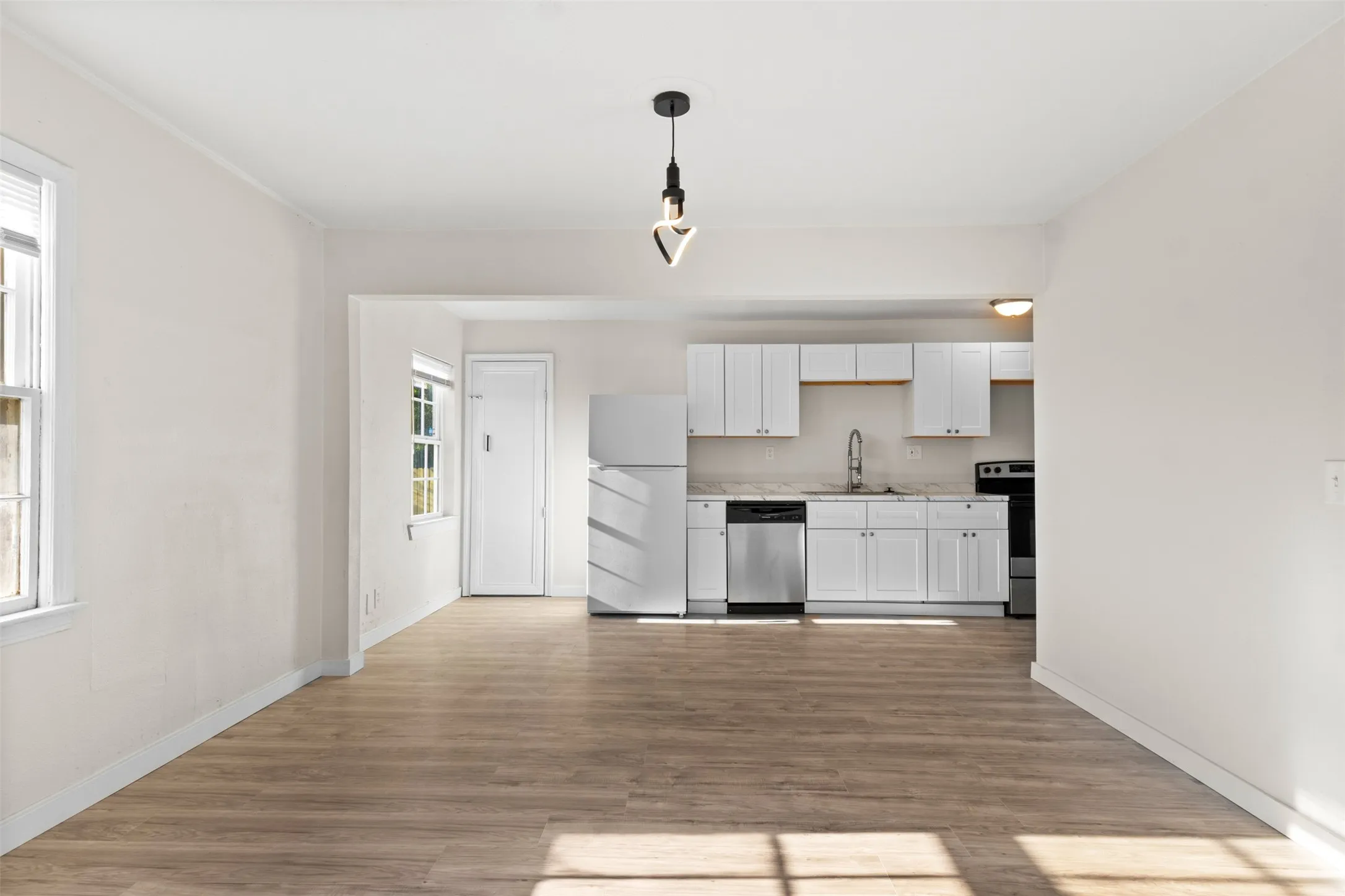 Open-concept living area with wood-finish flooring, recessed lighting, and ample natural light
