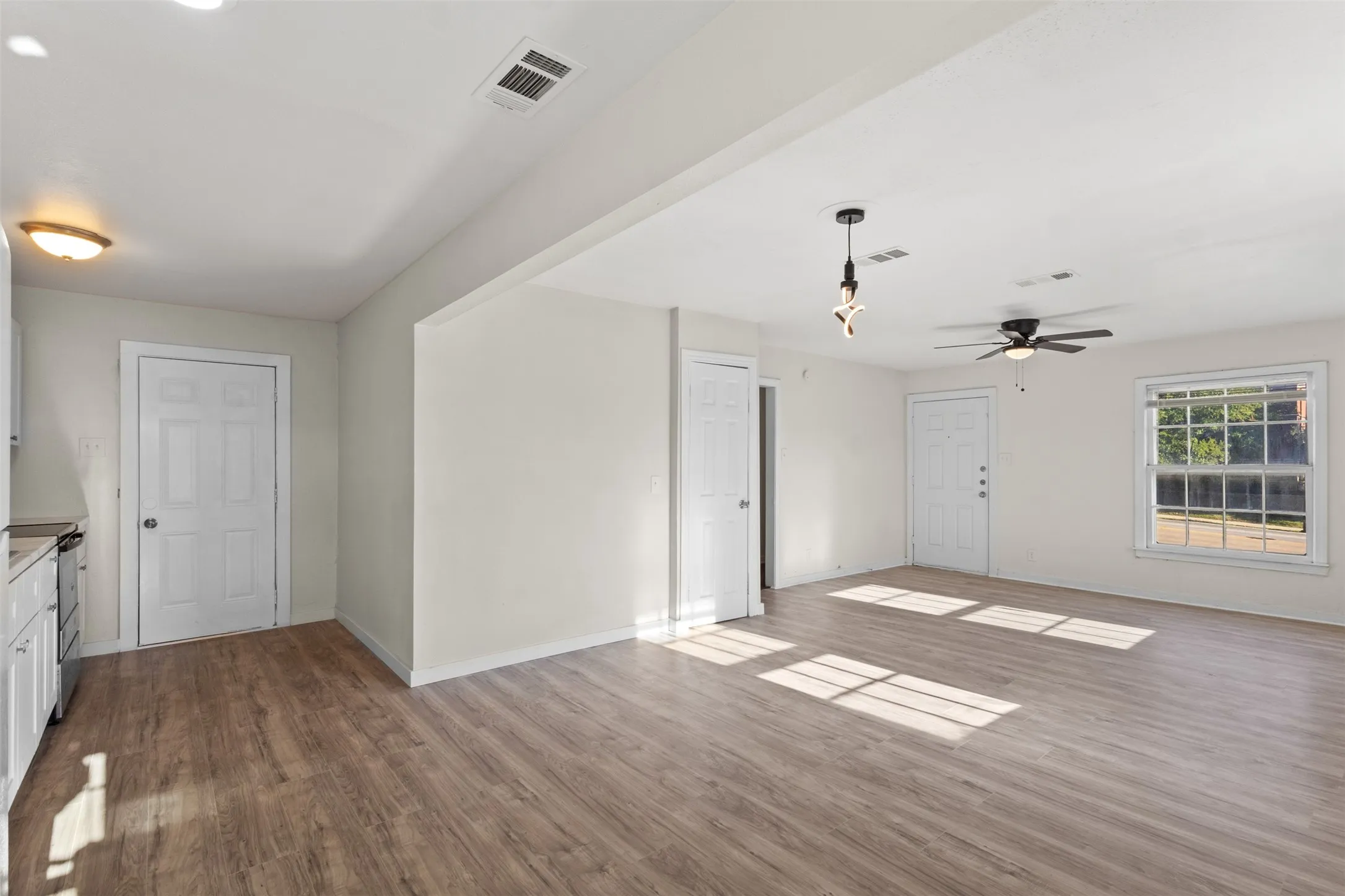Expansive room featuring wood-finish flooring, a ceiling fan, and multiple windows