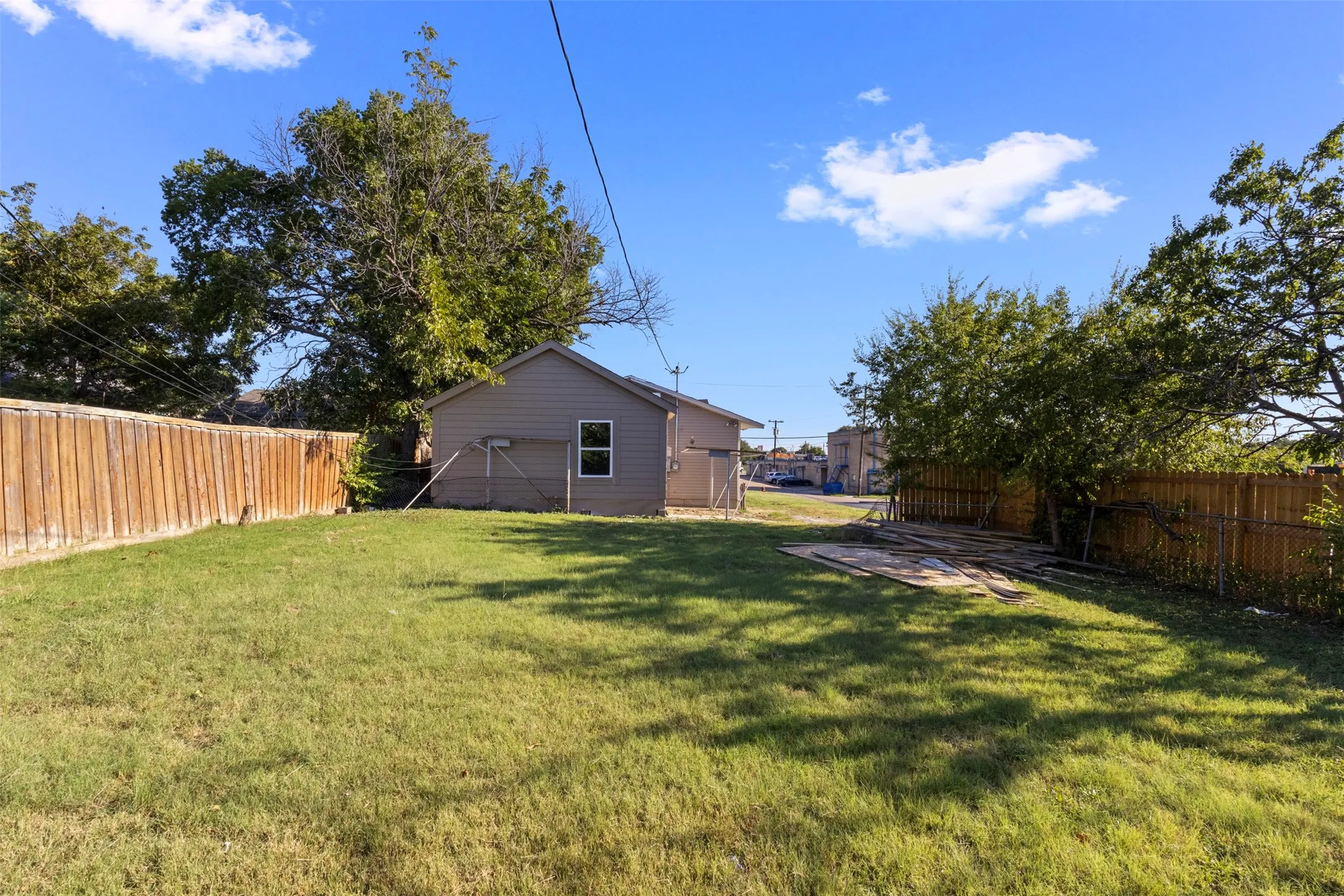 Expansive grassy yard with wood fencing and mature trees
