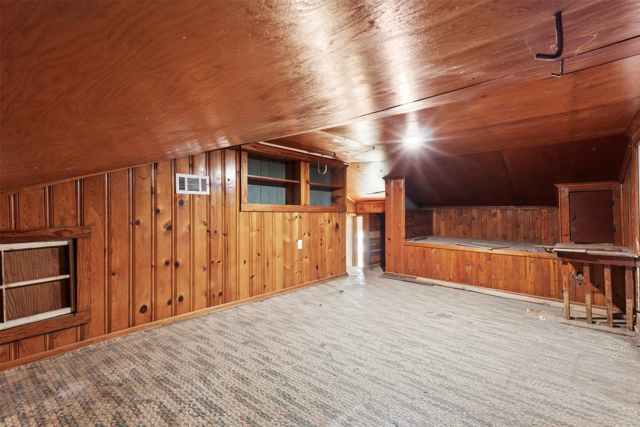 Wood paneling throughout, built-in shelving, vaulted wood-finish ceiling, and textured floor covering
