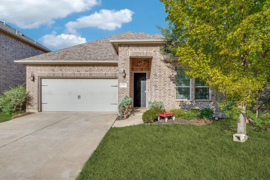 Brick exterior with a covered entry, attached two-car garage, and a concrete driveway