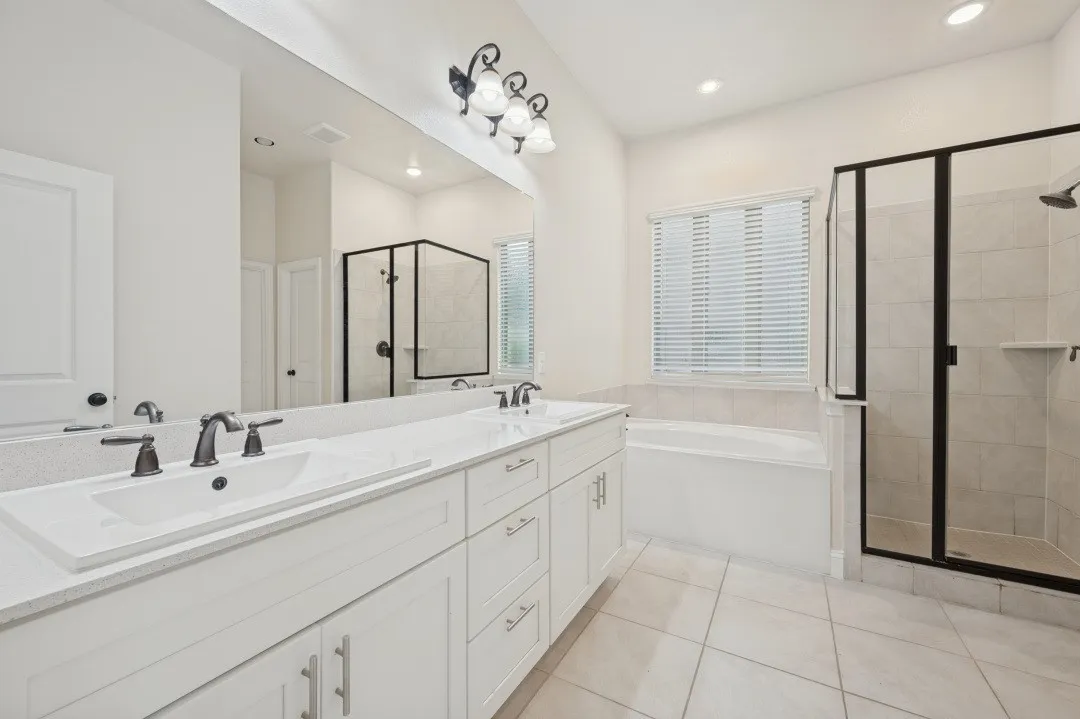 Dual vanity with integrated sinks, white cabinetry, and brushed nickel hardware