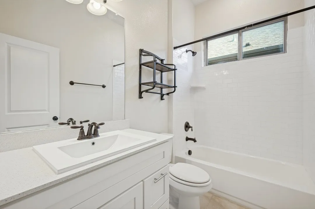 White shaker vanity with integrated sink, quartz-finish countertop, and bronze-tone fixtures