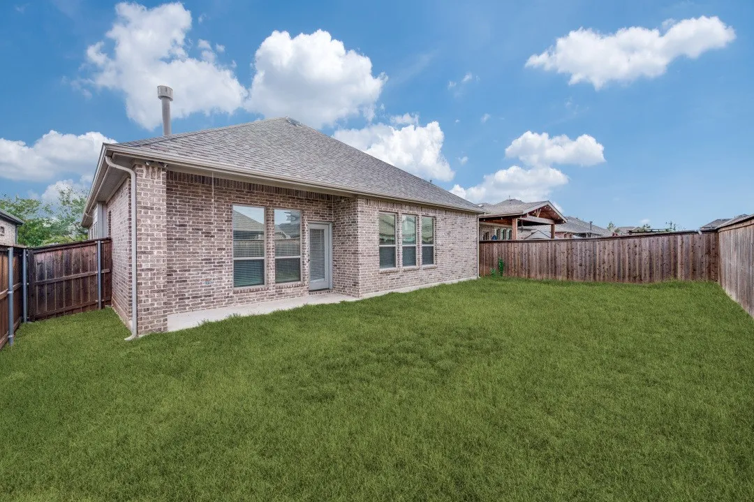 Expansive backyard featuring a manicured lawn, full privacy fencing, and a concrete patio