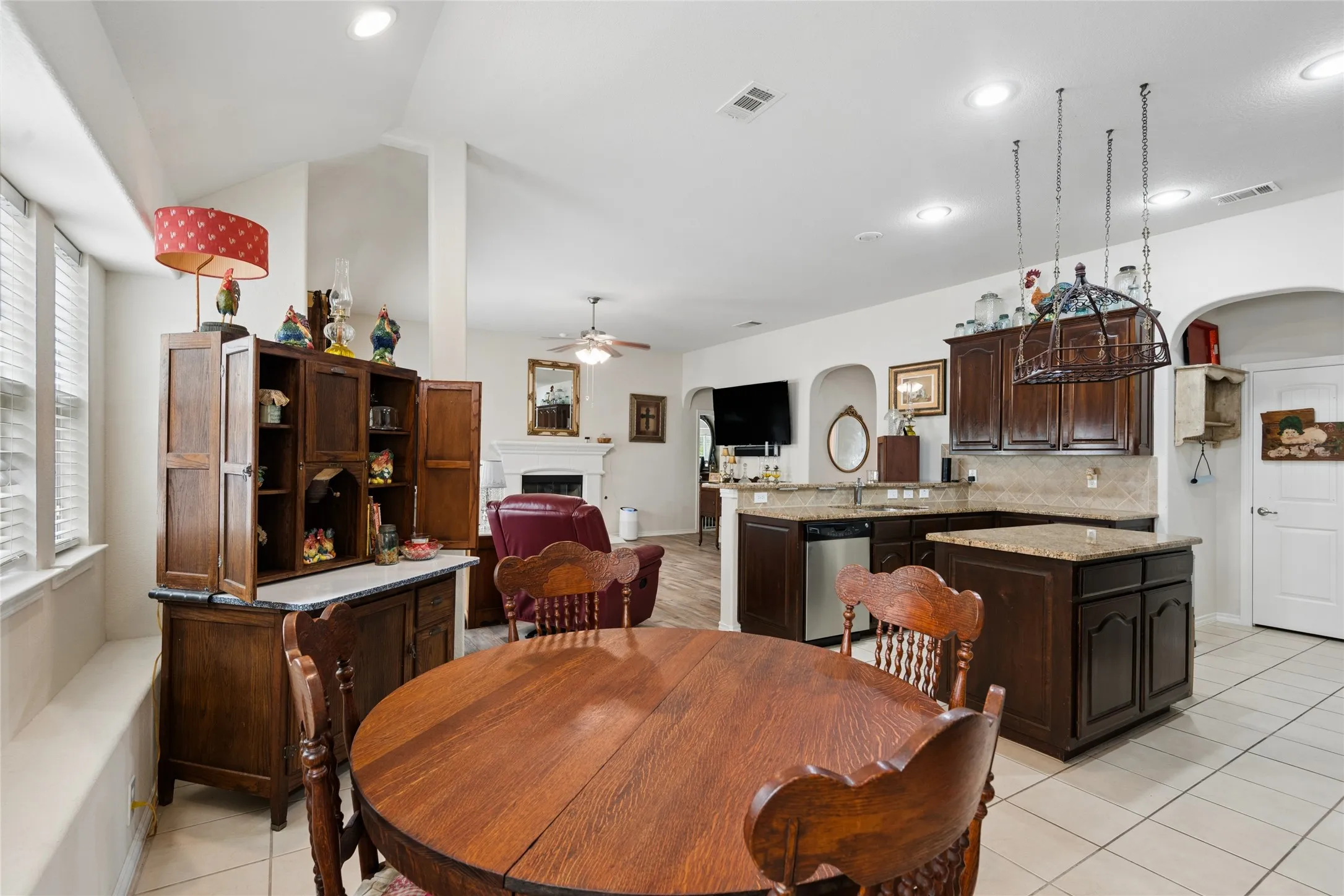 Open-concept living space with vaulted ceilings, a kitchen featuring dark wood cabinetry and granite countertops, and a dining area with tile flooring