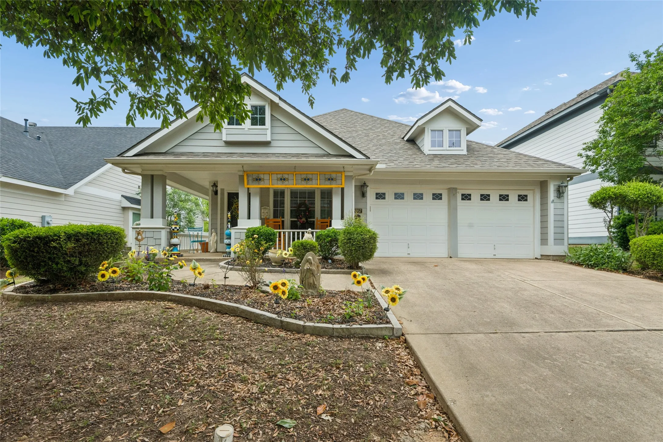 Front exterior featuring light gray siding, a covered porch, a two-car garage with white doors, and a concrete​​‌​​​​‌​​‌‌​‌‌​​​‌‌​‌​‌​‌​​​‌​​ driveway
