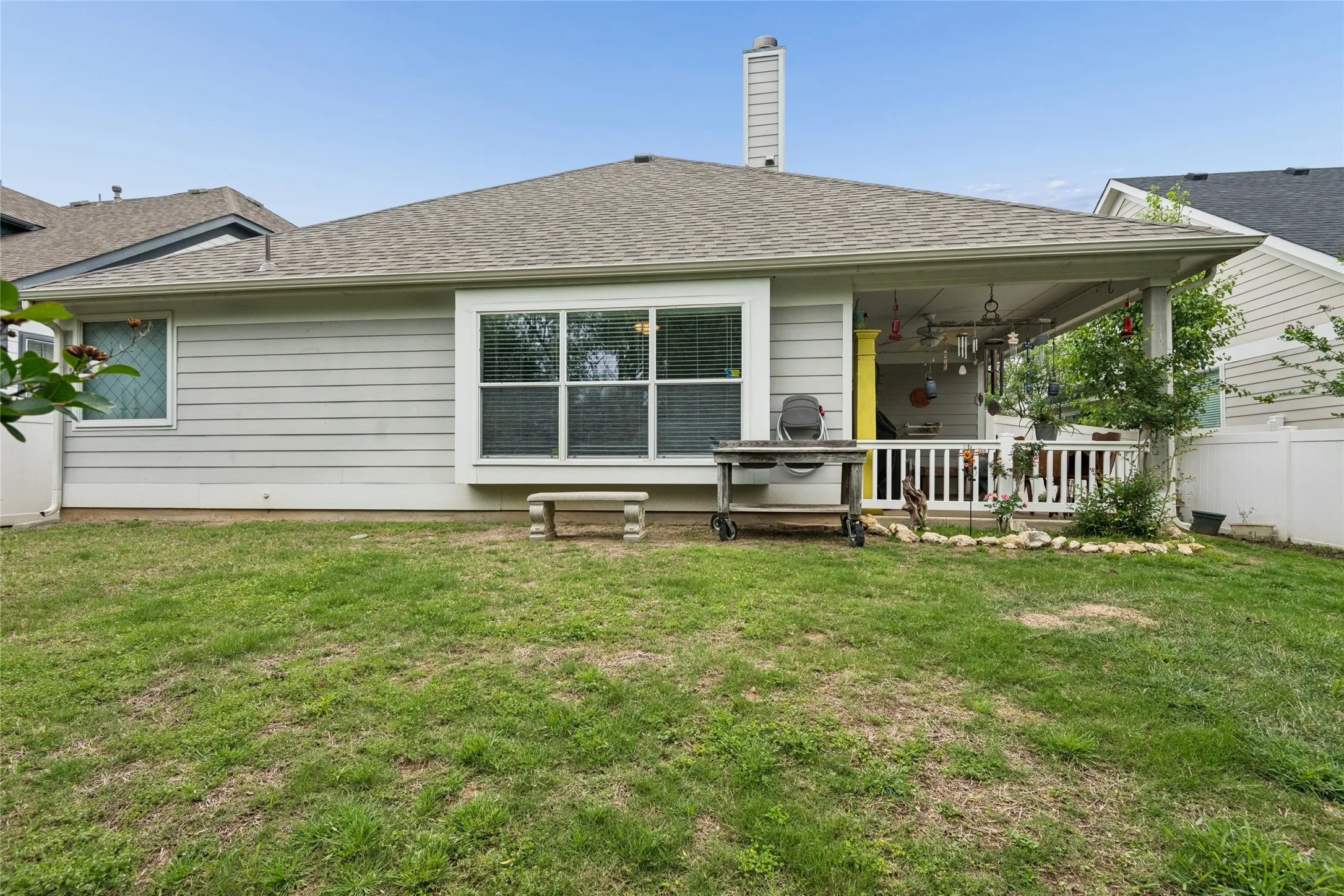 Rear exterior featuring a covered patio with railing, light-colored siding, and a fenced yard