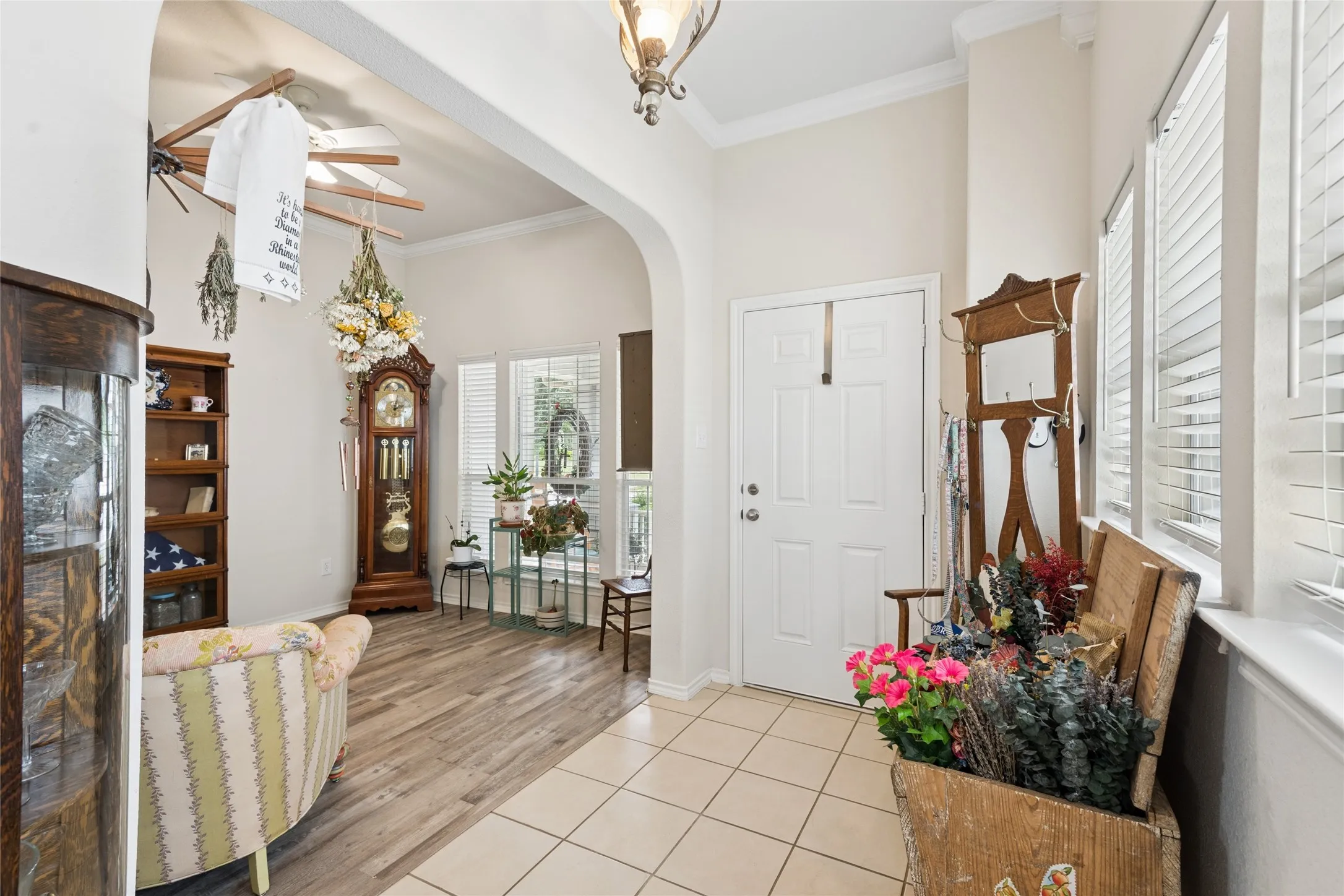 Archway entry with crown molding, tiled flooring, wood-finish flooring, and white window blinds