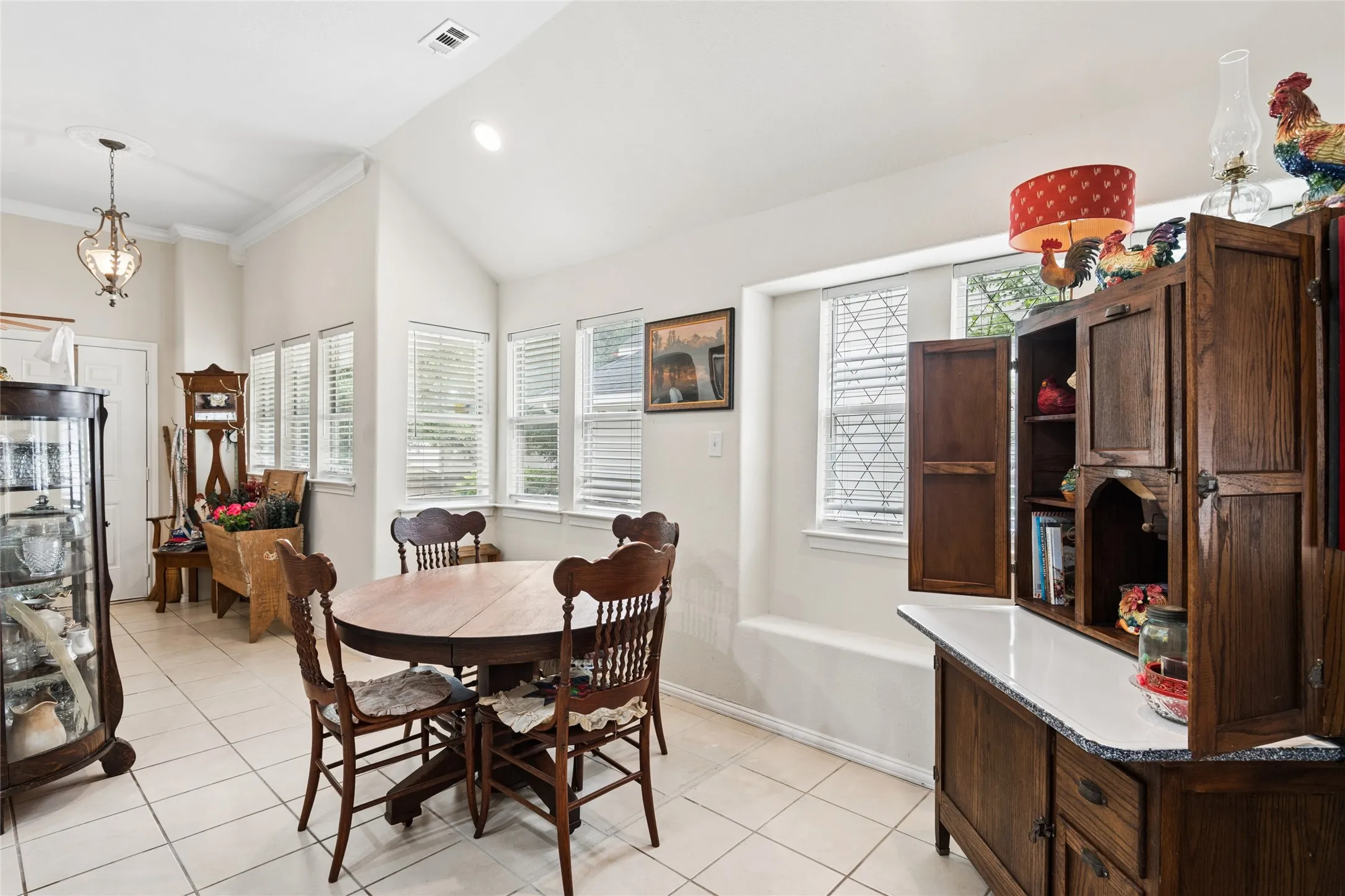 Vaulted ceiling with recessed lighting, tile flooring, window bench seating, and multiple windows with blinds