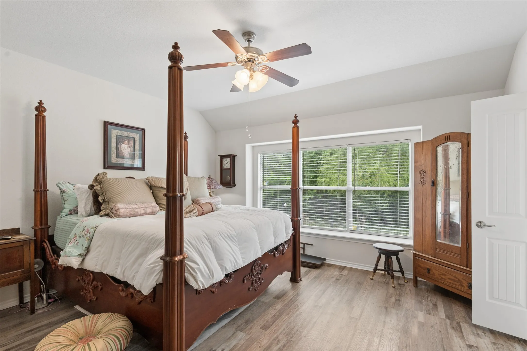 Vaulted ceiling featuring a ceiling fan, wood-finish flooring, and large windows with blinds