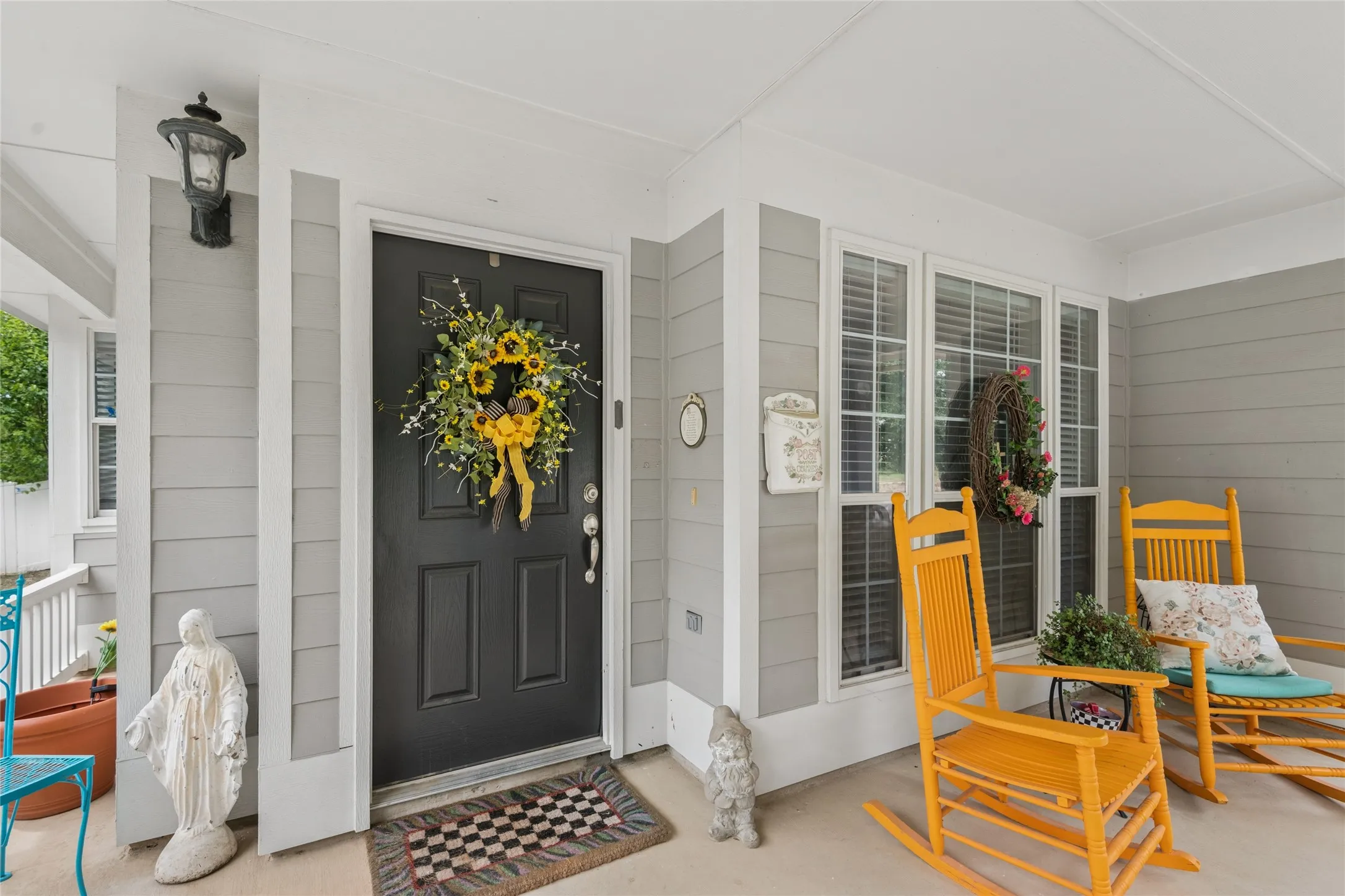 Covered front porch featuring gray horizontal siding and a dark paneled entry door