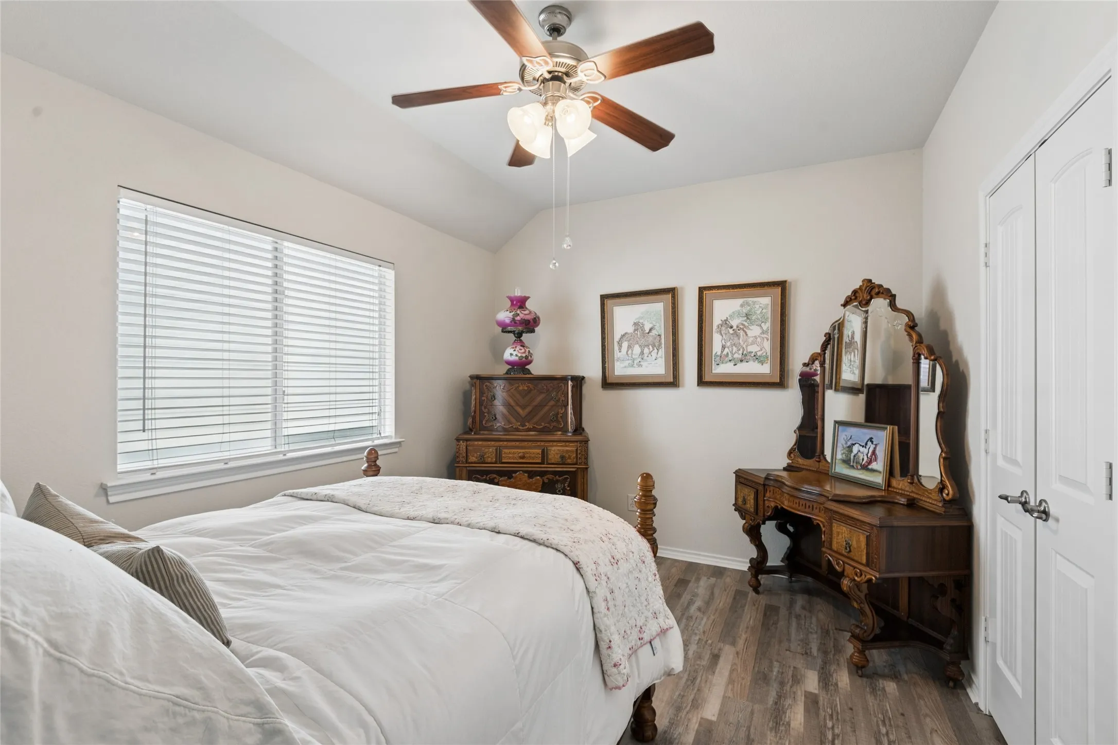 Vaulted ceiling with a ceiling fan light fixture, window with blinds, wood-finish flooring, and white bifold closet doors