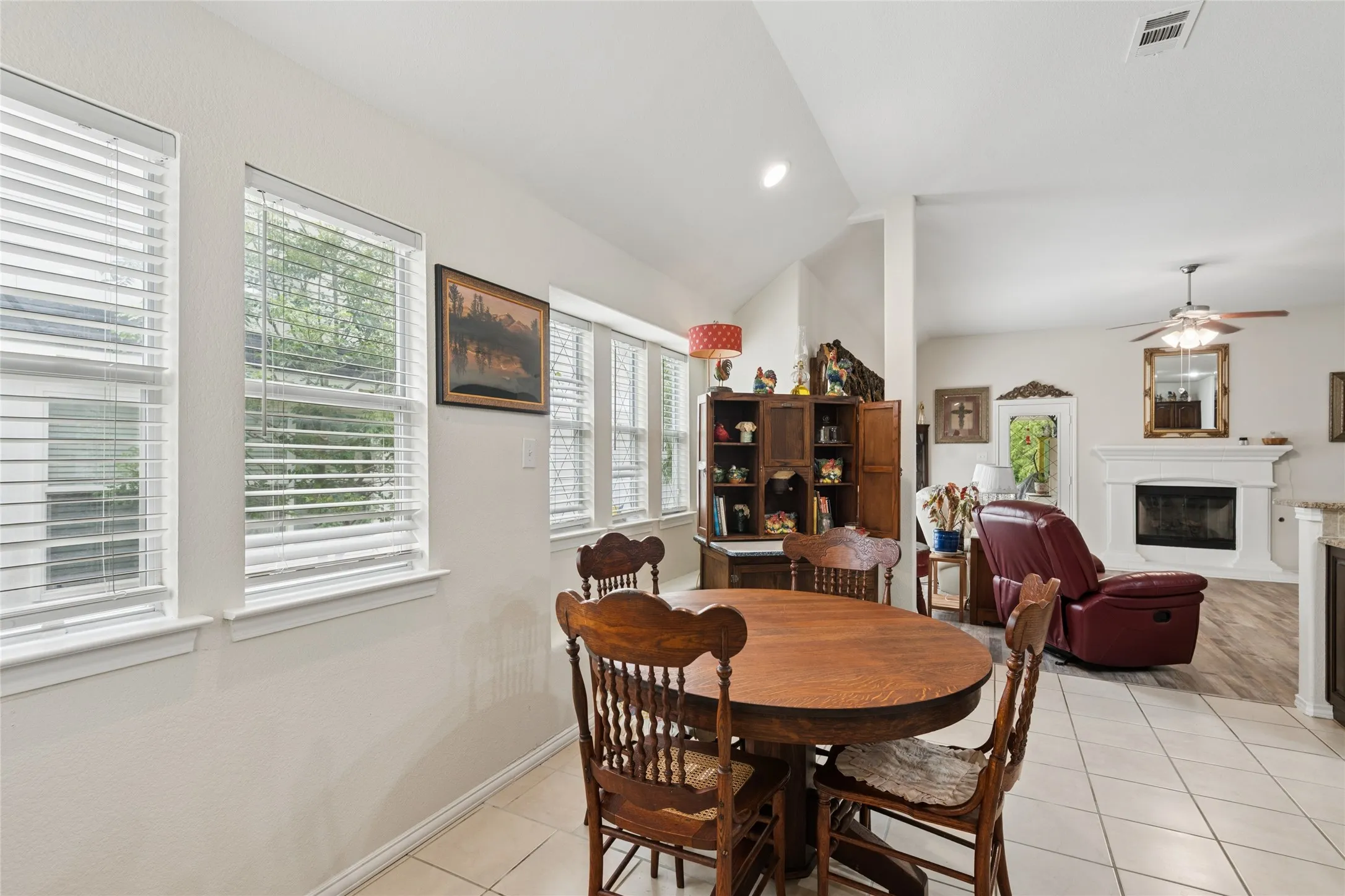 Tile flooring, multiple windows with blinds, recessed lighting, vaulted ceilings, and a fireplace with a mantel