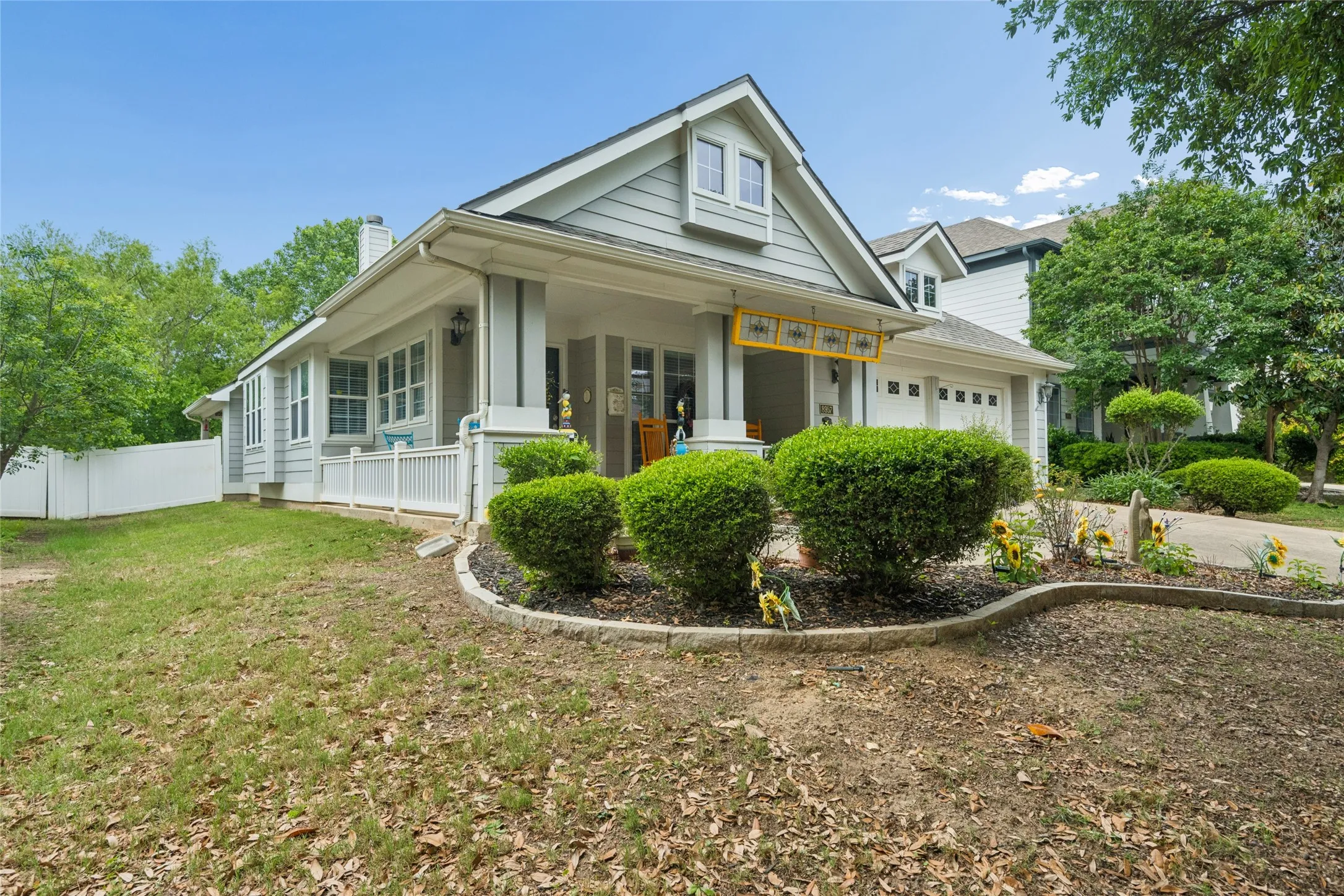Light gray siding exterior with a white trim, front porch with column supports, and a two-car garage