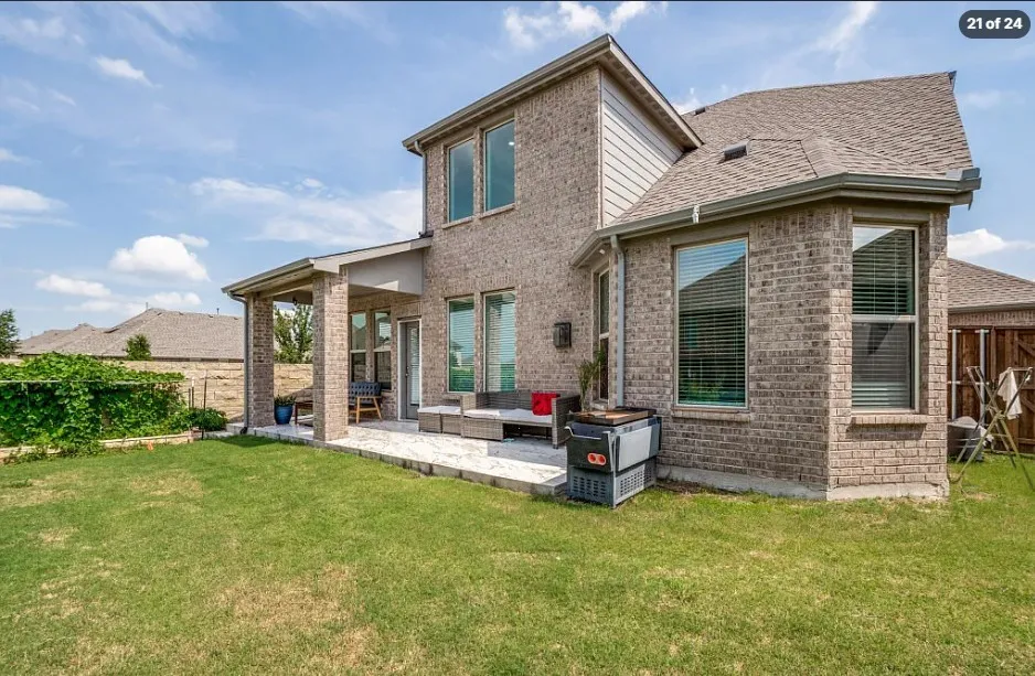 Expansive backyard featuring a covered patio, brick exterior, bay window, and a shingled roof