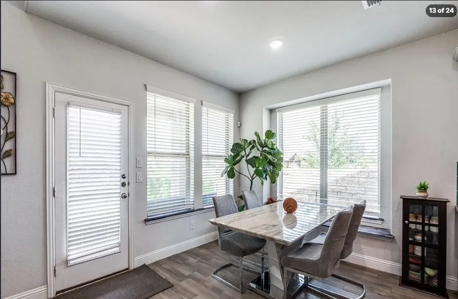 Recessed ceiling lighting, multiple large windows, wood-finish flooring, and a white door with integrated blinds