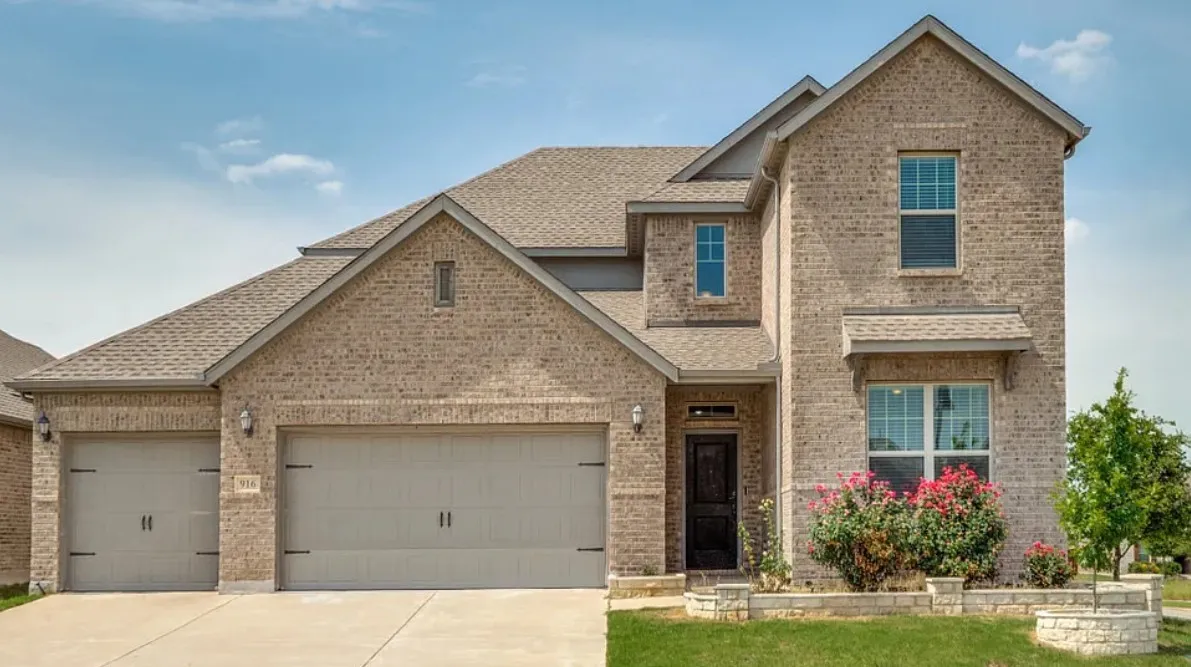 Brick exterior with a multi-level roofline, two-car garage, and a single-car garage