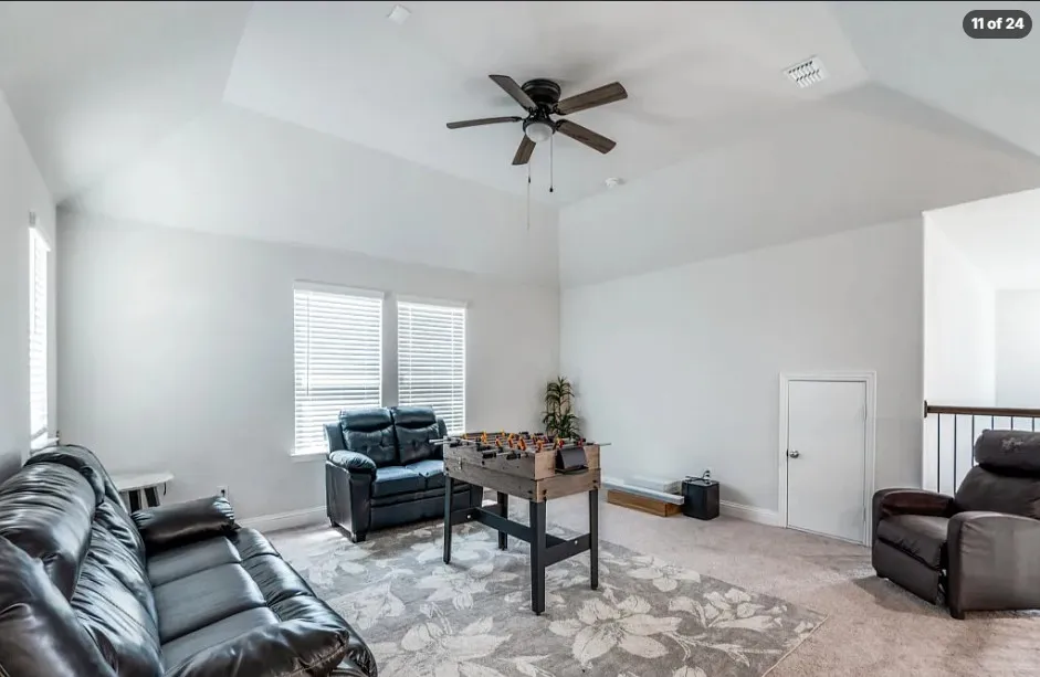 Vaulted ceiling with a ceiling fan, carpeted flooring, multiple windows with blinds, and white interior walls