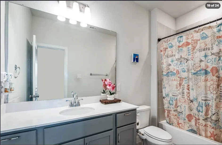 Bathroom featuring a single vanity with gray cabinetry, a white countertop, and a chrome faucet