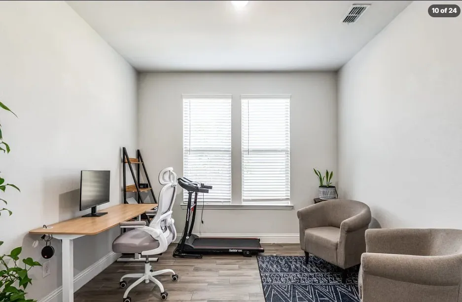 Dual windows with blinds, light wood-finish flooring, and crisp white walls