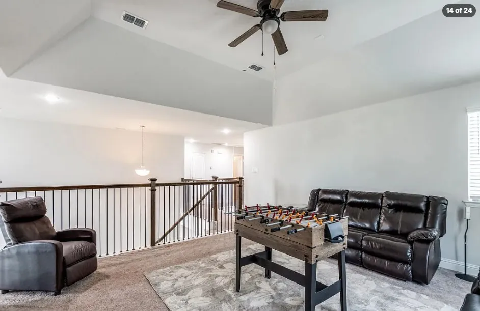Vaulted ceiling, ceiling fan, carpeted flooring, window with blinds, and wood and iron railing