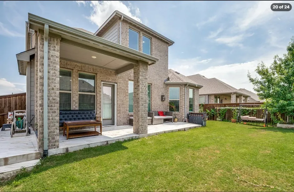 Expansive backyard featuring a manicured lawn, a covered patio, and a separate uncovered patio area