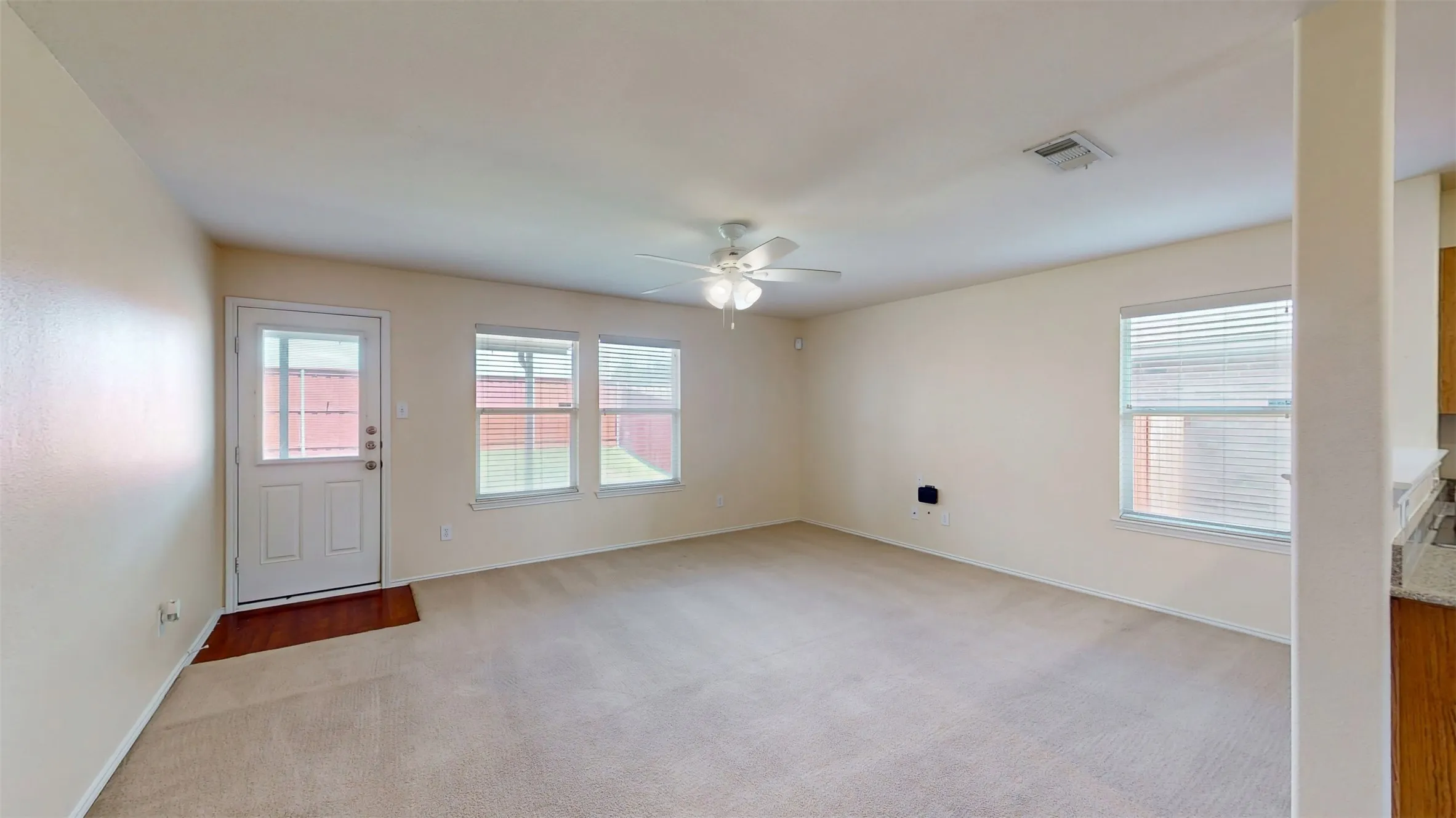 Spacious living room, complete with a ceiling fan, upgraded window blinds, and crisp, clean carpet! Living room looks out to backyard.