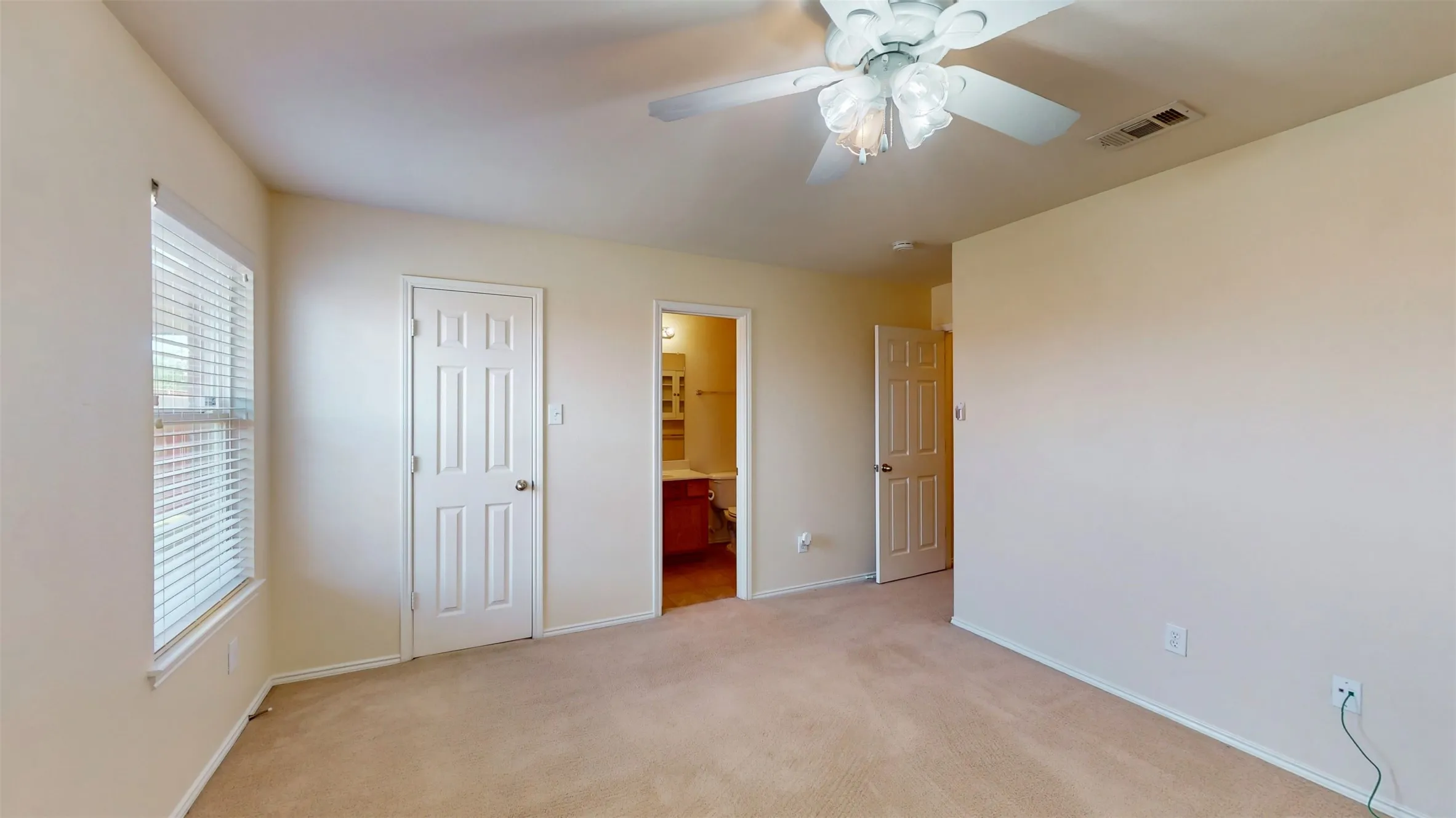 Primary suite is complete with window blinds, a ceiling fan, a separate walk-in closet, and its own private bathroom.
