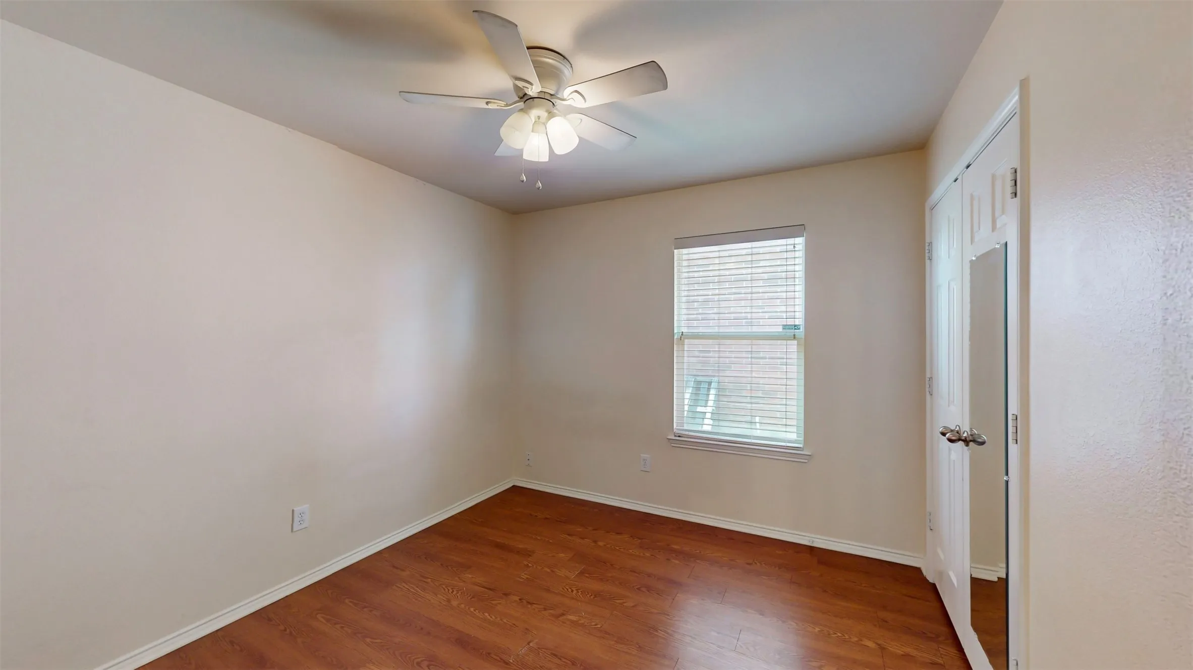 Bedroom 2 with wood-look flooring, window blinds, and a ceiling fan.