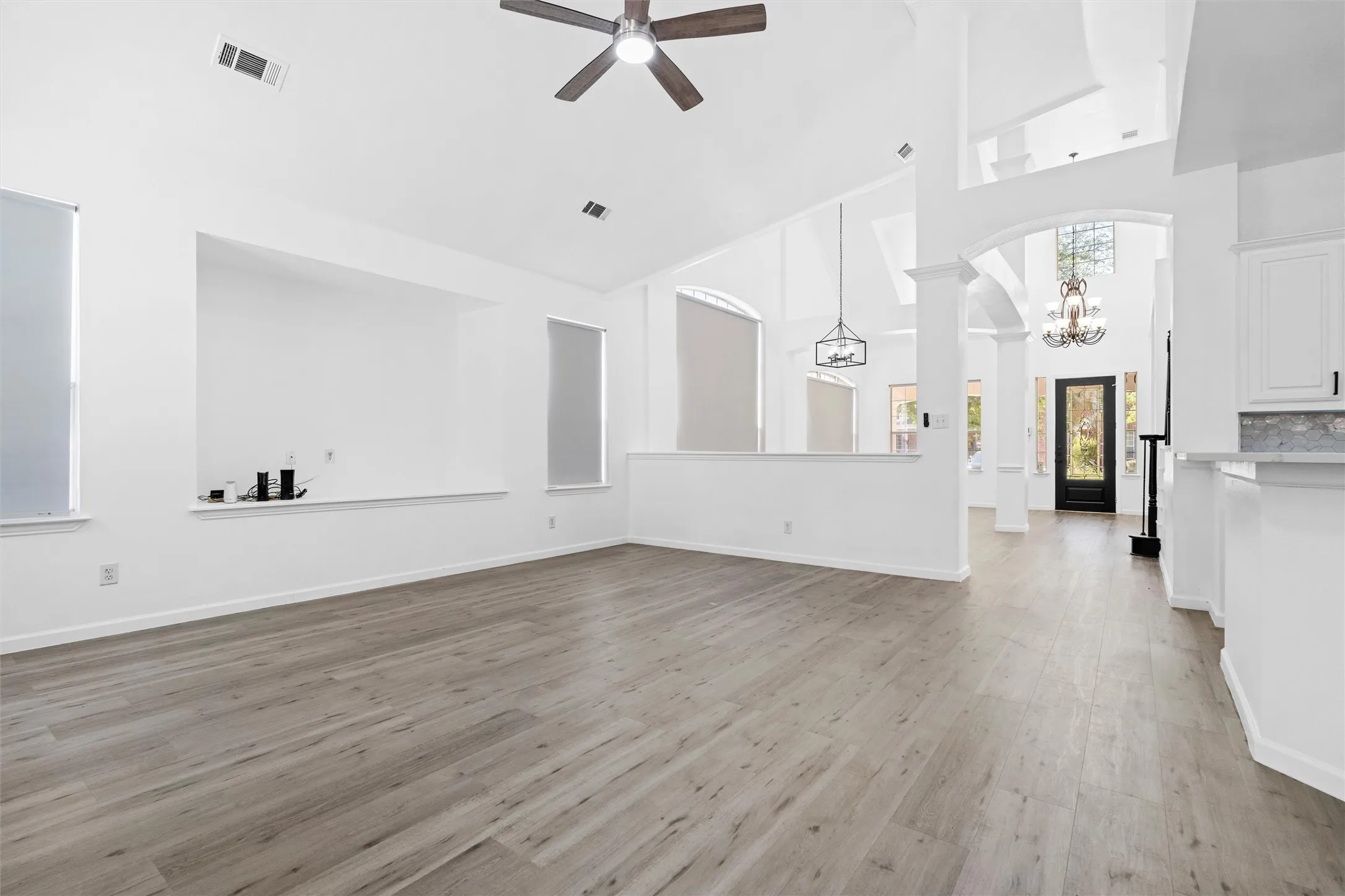 Vaulted ceilings, wood-finish flooring, ceiling fan, arched doorways, and built-in shelving