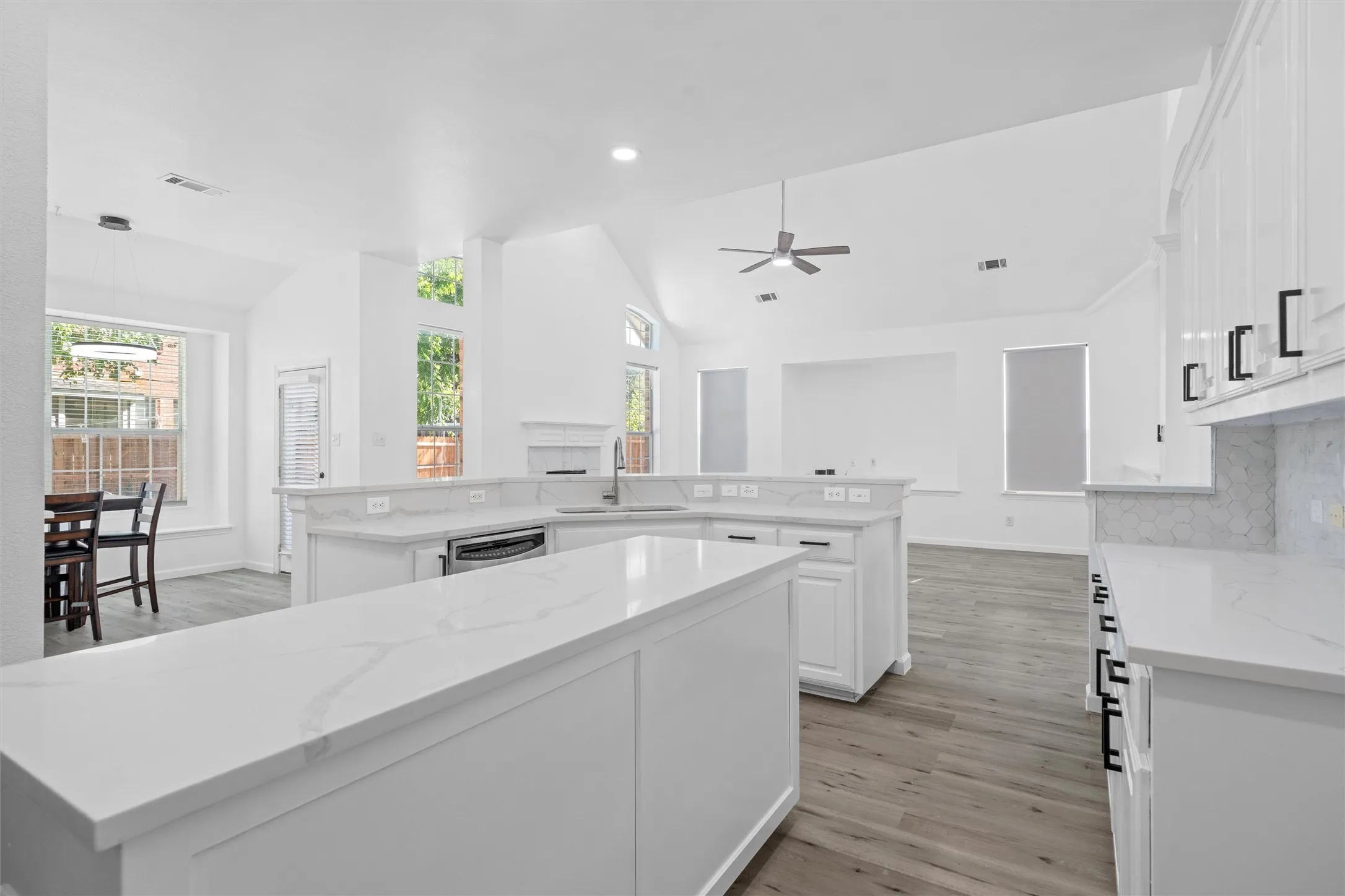 Kitchen featuring white cabinetry, light-toned countertops, a tile backsplash, and wood-finish flooring