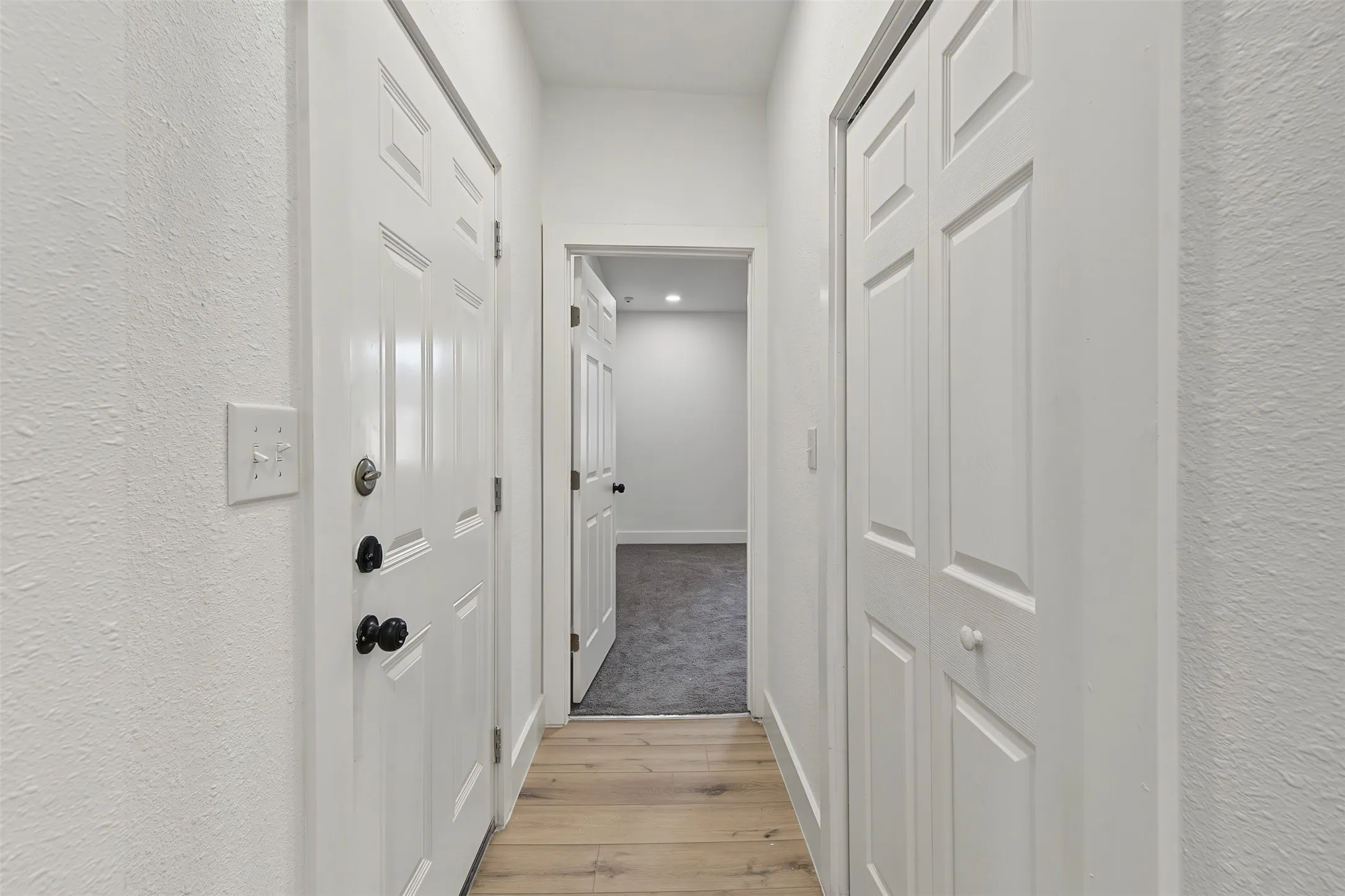 Hallway featuring wood-finish flooring, white panel doors, and a bi-fold closet