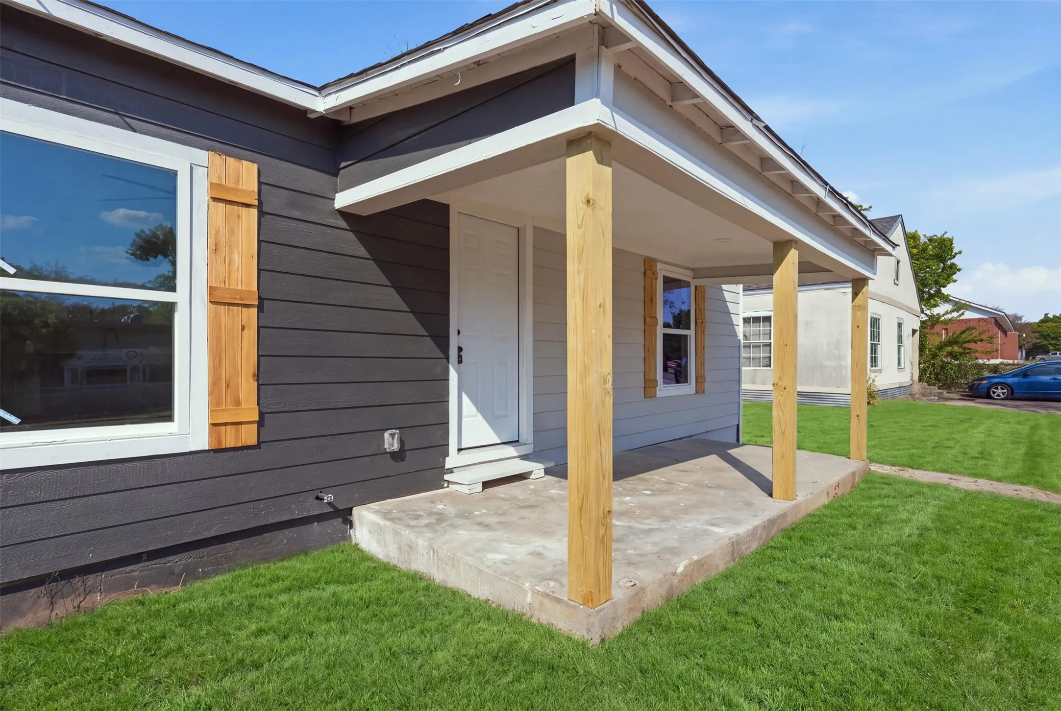 Front facade with dark siding, white trim, and natural wood shutters