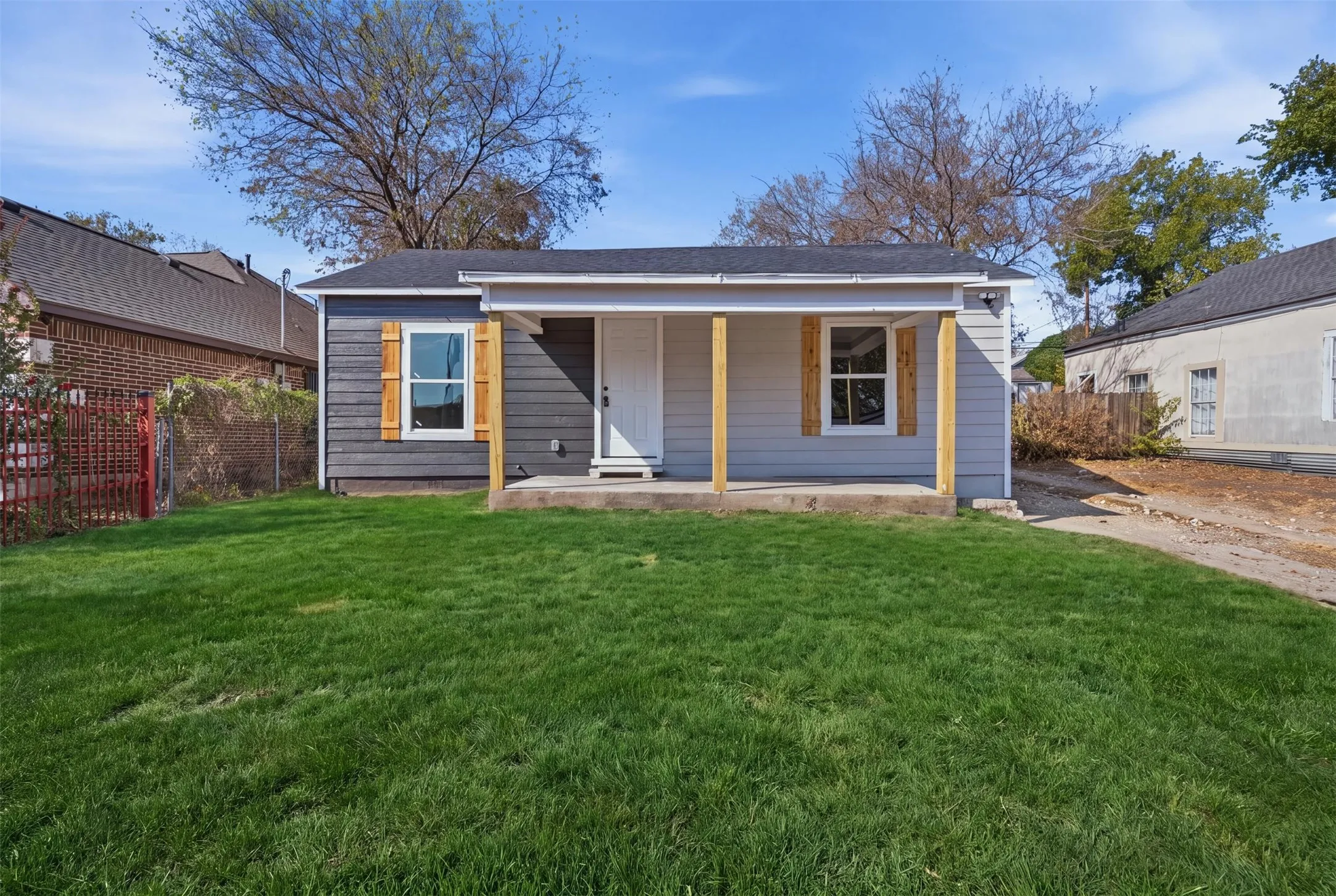 Exterior featuring horizontal siding, a covered porch with wood posts, wood window shutters, a dark shingle roof, and a front lawn