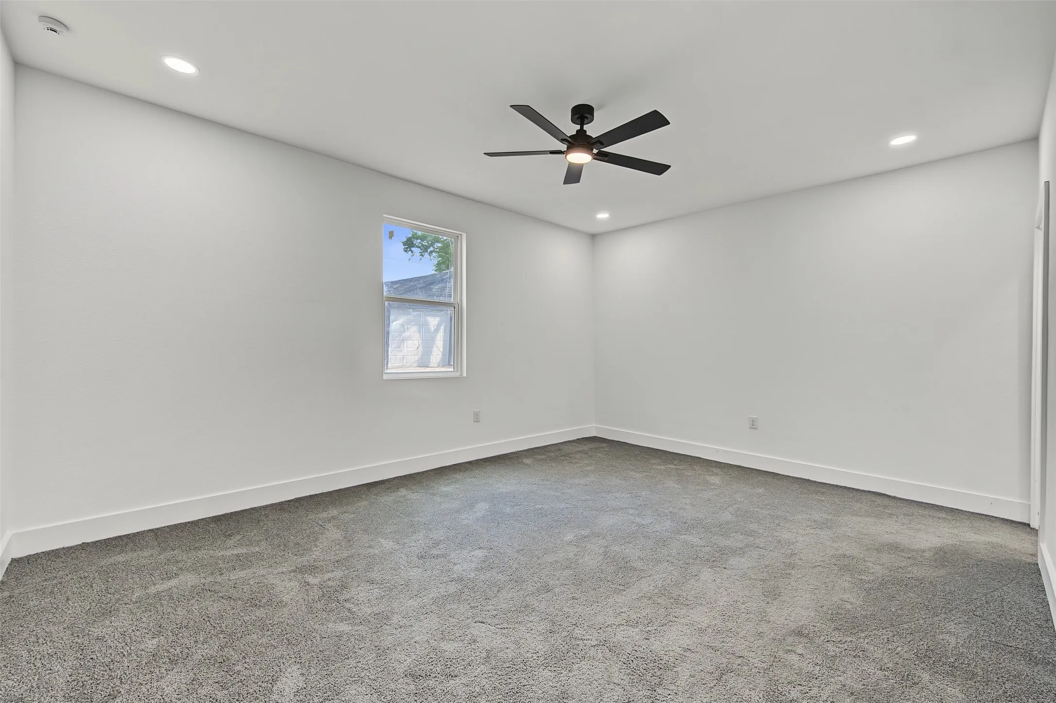 Recessed lighting, ceiling fan with integrated light, carpeted flooring, and a single window