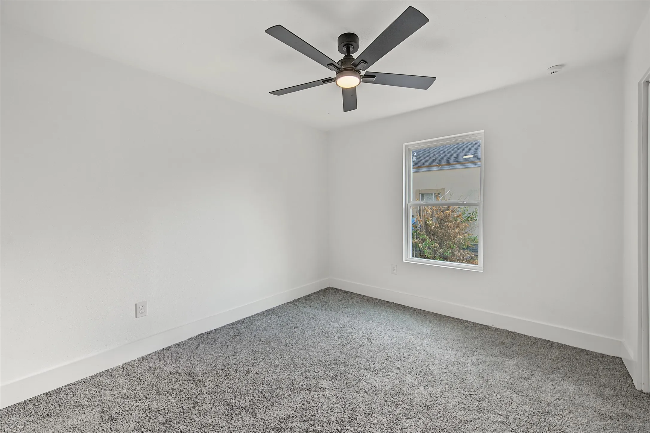 Recessed lighting, ceiling fan with integrated light, white walls, gray carpeting, and a window with white trim