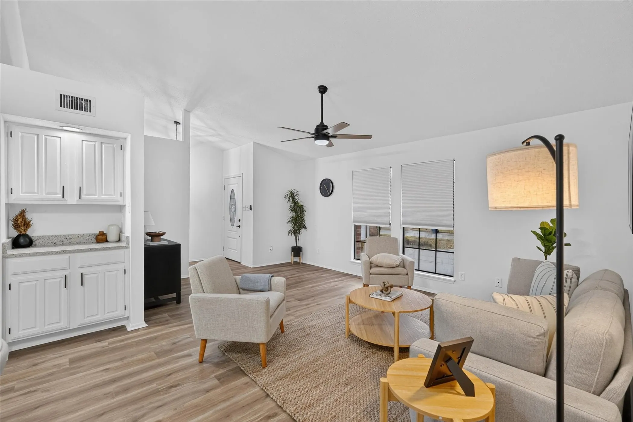 Vaulted ceiling, wood-finish flooring, built-in cabinetry with stone-look countertop, ceiling fan with integrated lighting, and a front entry door with an oval glass insert