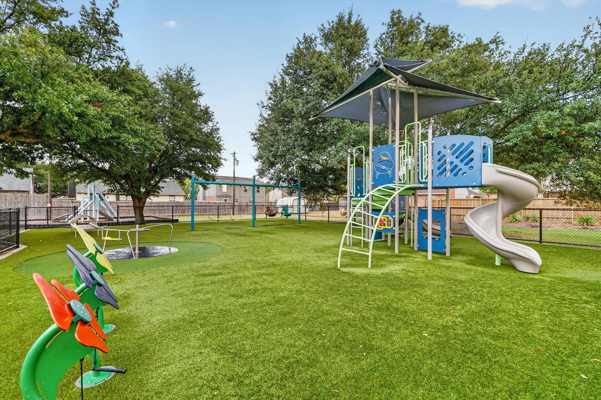 Recreation area featuring a comprehensive play structure with a spiral slide, shaded canopy, and climbing elements