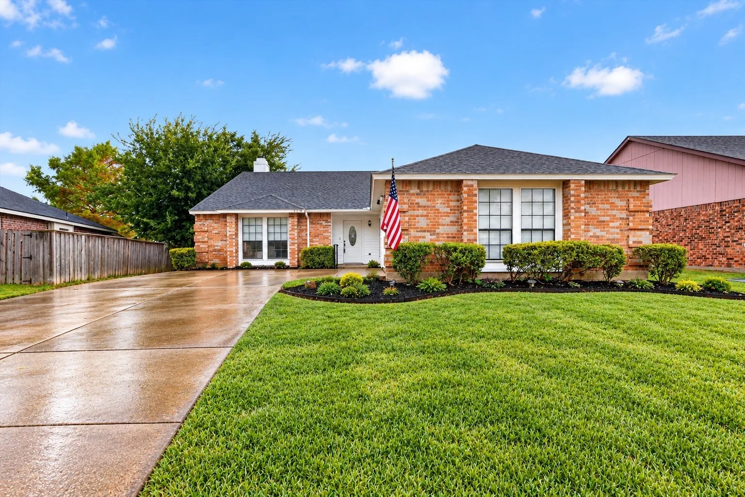 Brick exterior, dark shingle roof, expansive front lawn, mature landscaping, and concrete driveway