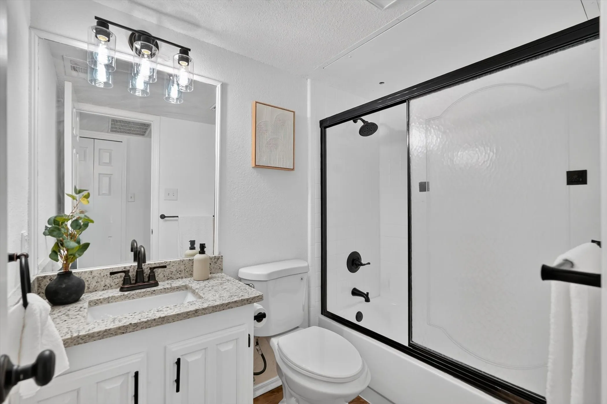 Vanity with a granite-style countertop, white cabinetry, and matte black hardware