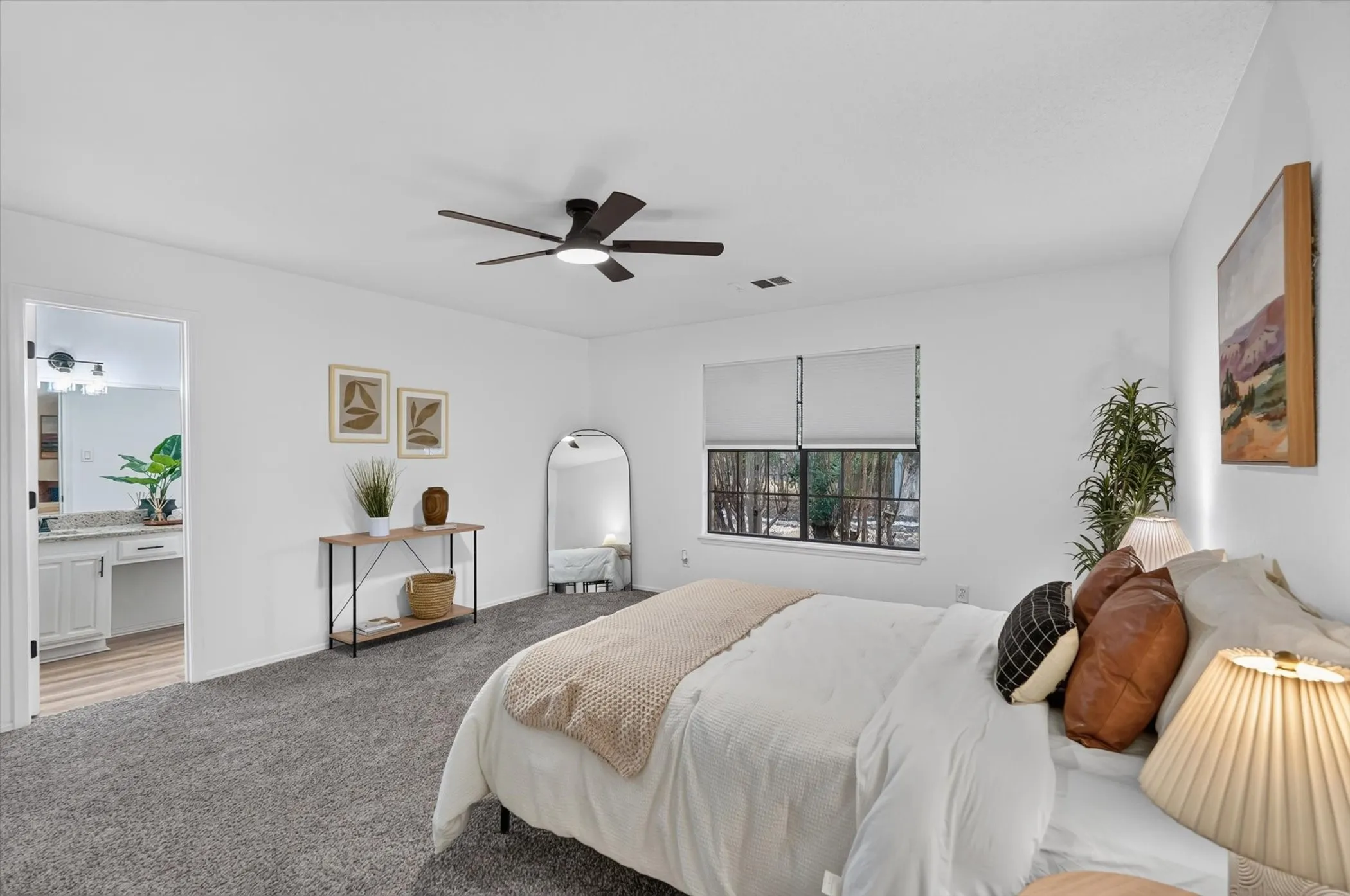Spacious room with plush carpeting, a large window, a ceiling fan with integrated lighting, and an attached bathroom