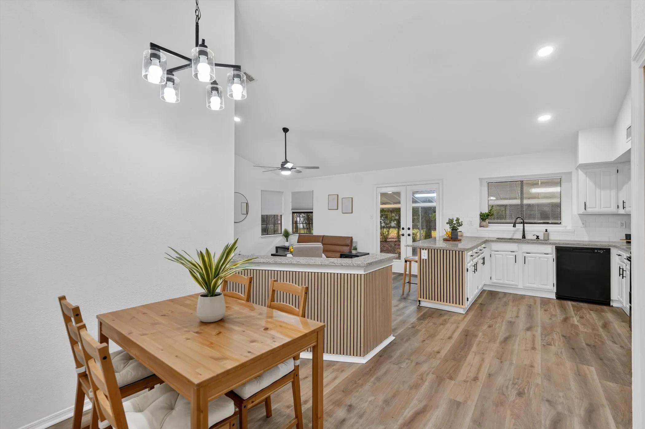 Open concept layout with wood-finish flooring, white cabinetry, recessed lighting, and a modern chandelier