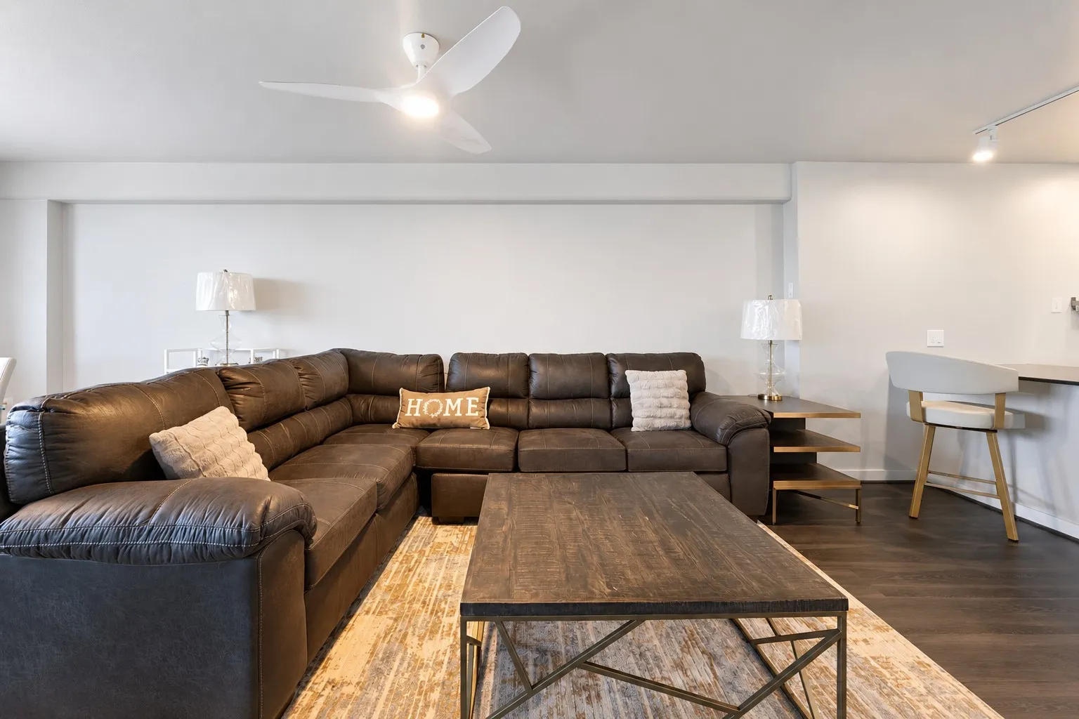White walls, ceiling fan with integrated lighting, wood-finish flooring, track lighting, and a built-in counter surface