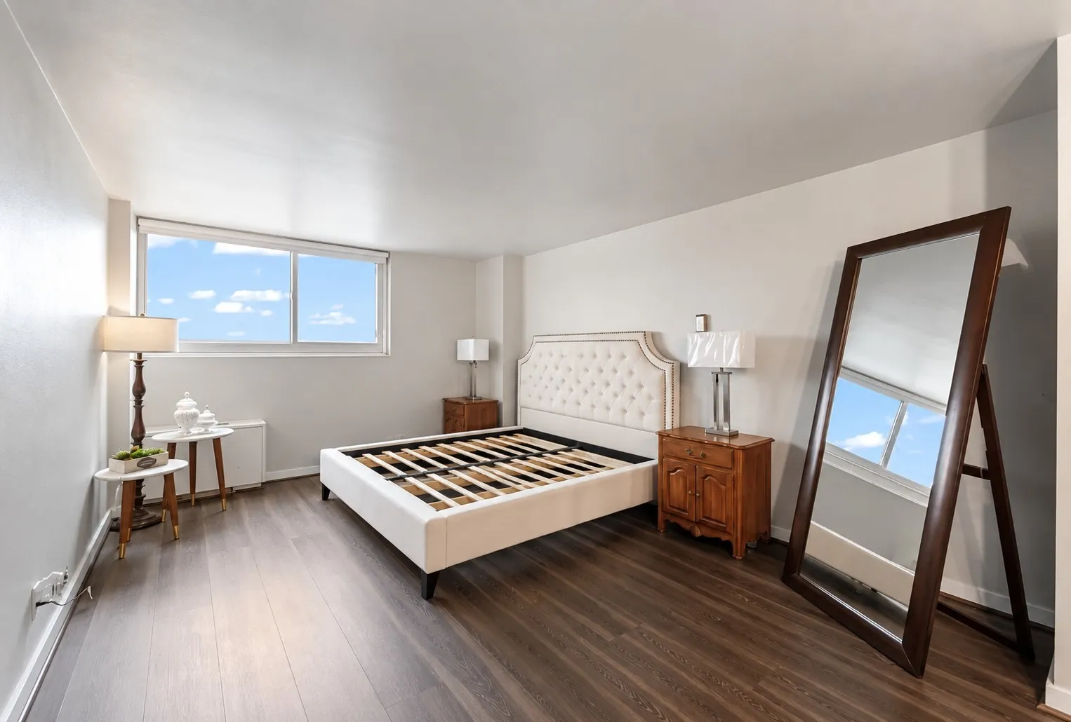 Expansive room with wood-finish flooring, a large window, light-toned walls, and a built-in air conditioning unit